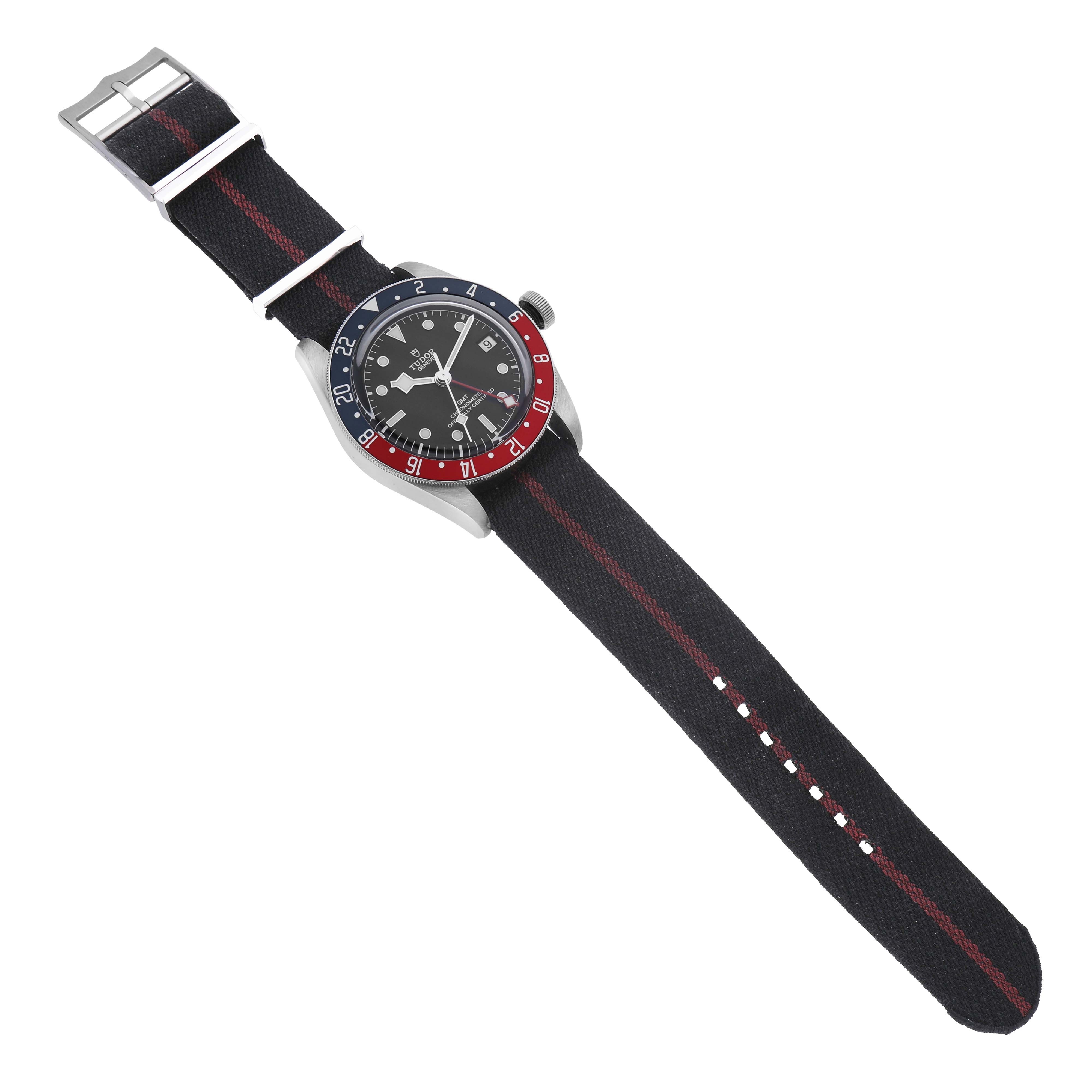 The Tudor Heritage Black Bay 79830RB Men's Stainless Steel Black Dial watch is shown from an overhead angle, displaying the bezel, dial, and NATO strap.