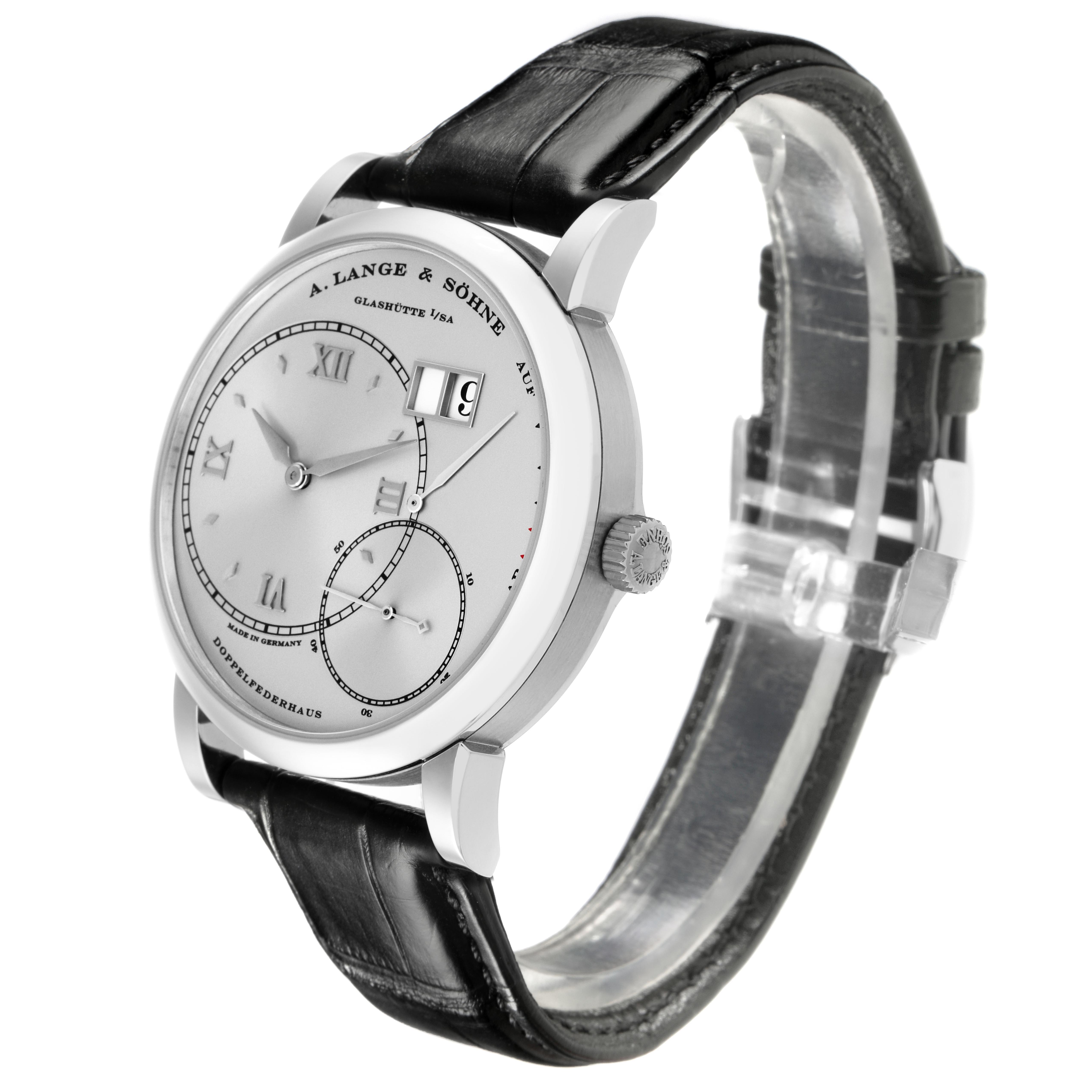 The A. Lange & Sohne Lange 1 115.026 Men's Platinum Silver Dial watch is shown at a three-quarter angle, featuring the dial, date display, crown, and black leather strap.