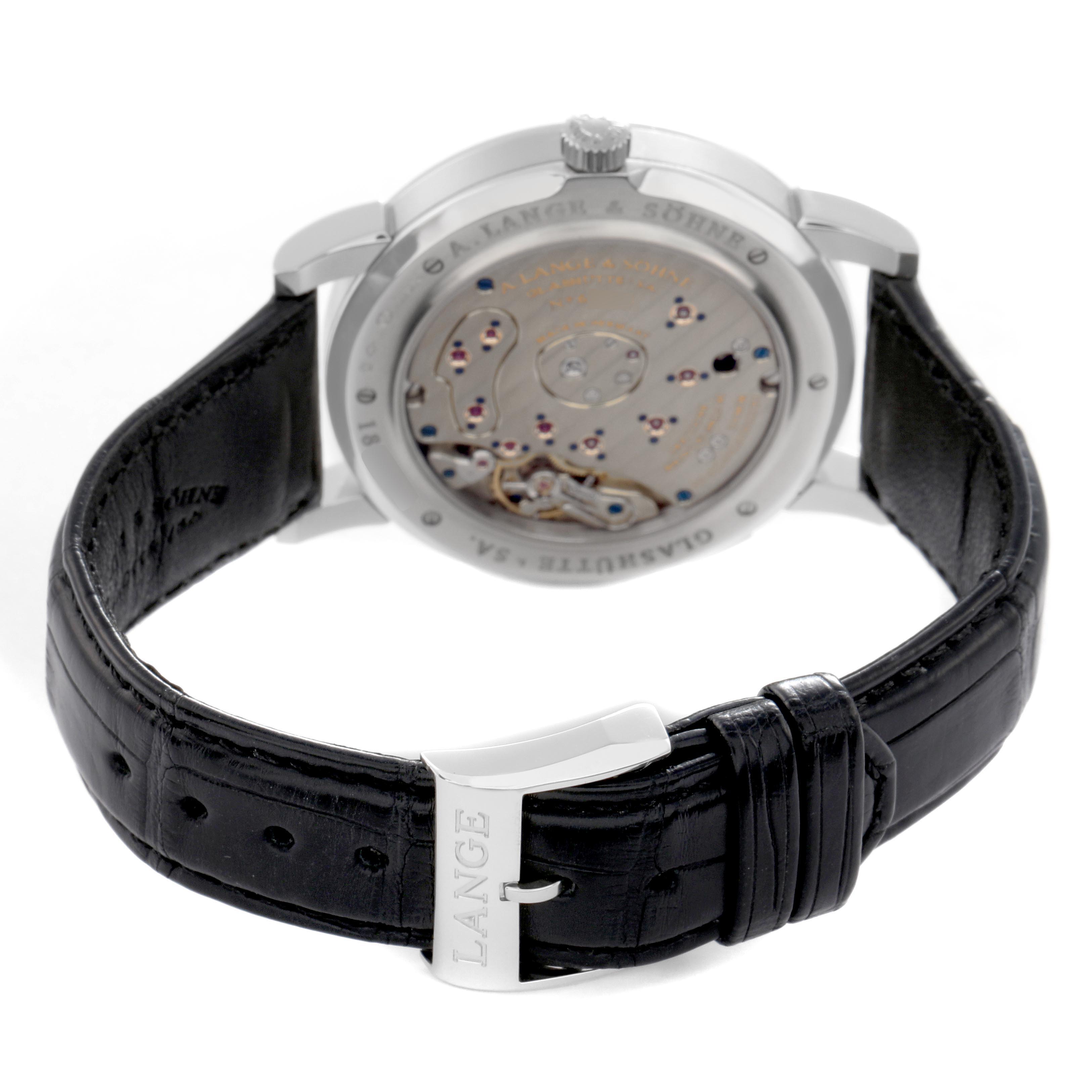 The image shows the back of a Lange 1 by A. Lange & Söhne, highlighting the movement and black leather strap.