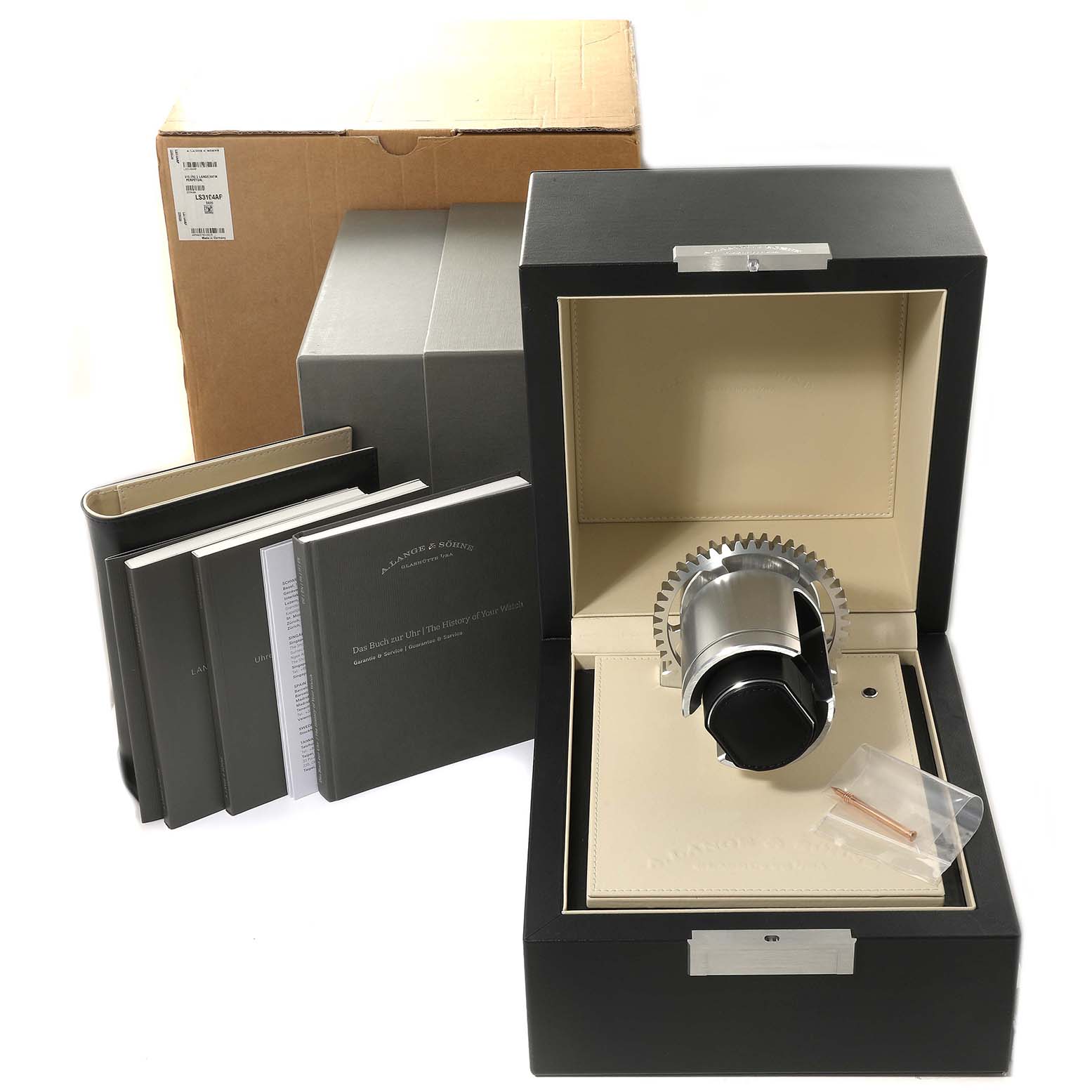 The image shows the Richard Lange model by A. Lange & Söhne from a front angle, featuring the watch winder, manuals, and packaging.