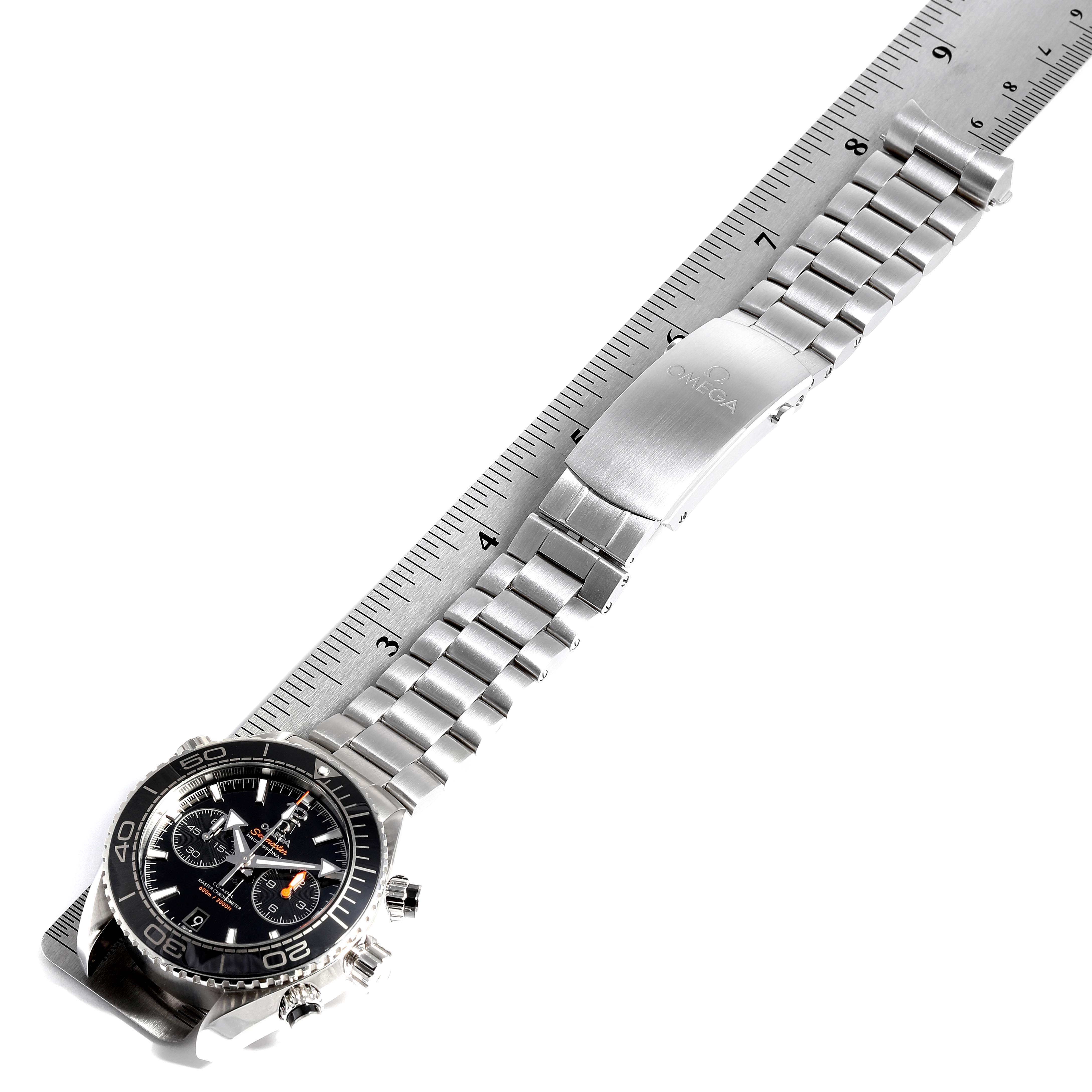 The image shows the Omega Planet Ocean 215.30.46.51.01.001 Men
s Stainless Steel Black Dial 215.30.46.51.01.001 Men
s Stainless Steel Black Dial watch at an angle, emphasizing the face and stainless steel bracelet, placed beside a ruler.