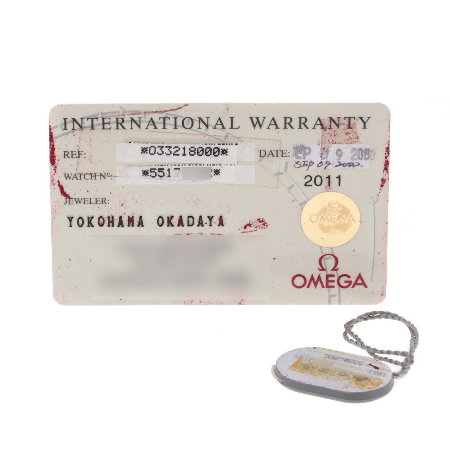 The image shows the international warranty card and tag for the Omega Speedmaster 3321.80.00 Men's Steel and Gold (two tone) Blue Dial 3321.80.00 Men's Steel and Gold (two tone) Blue Dial watch.