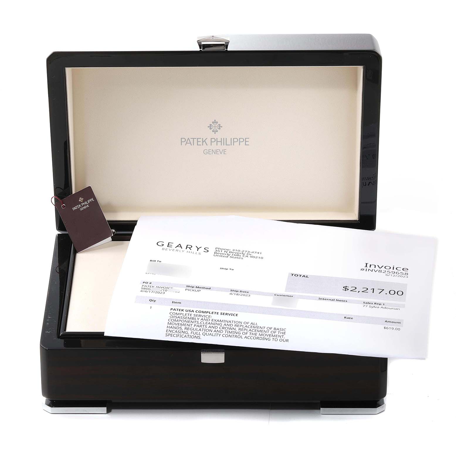 The image shows an open Patek Philippe Nautilus 7010R-012 Women's Rose Gold Champagne Dial 7010R-012 Women's Rose Gold Champagne Dial watch box with a tag and an invoice placed on top.