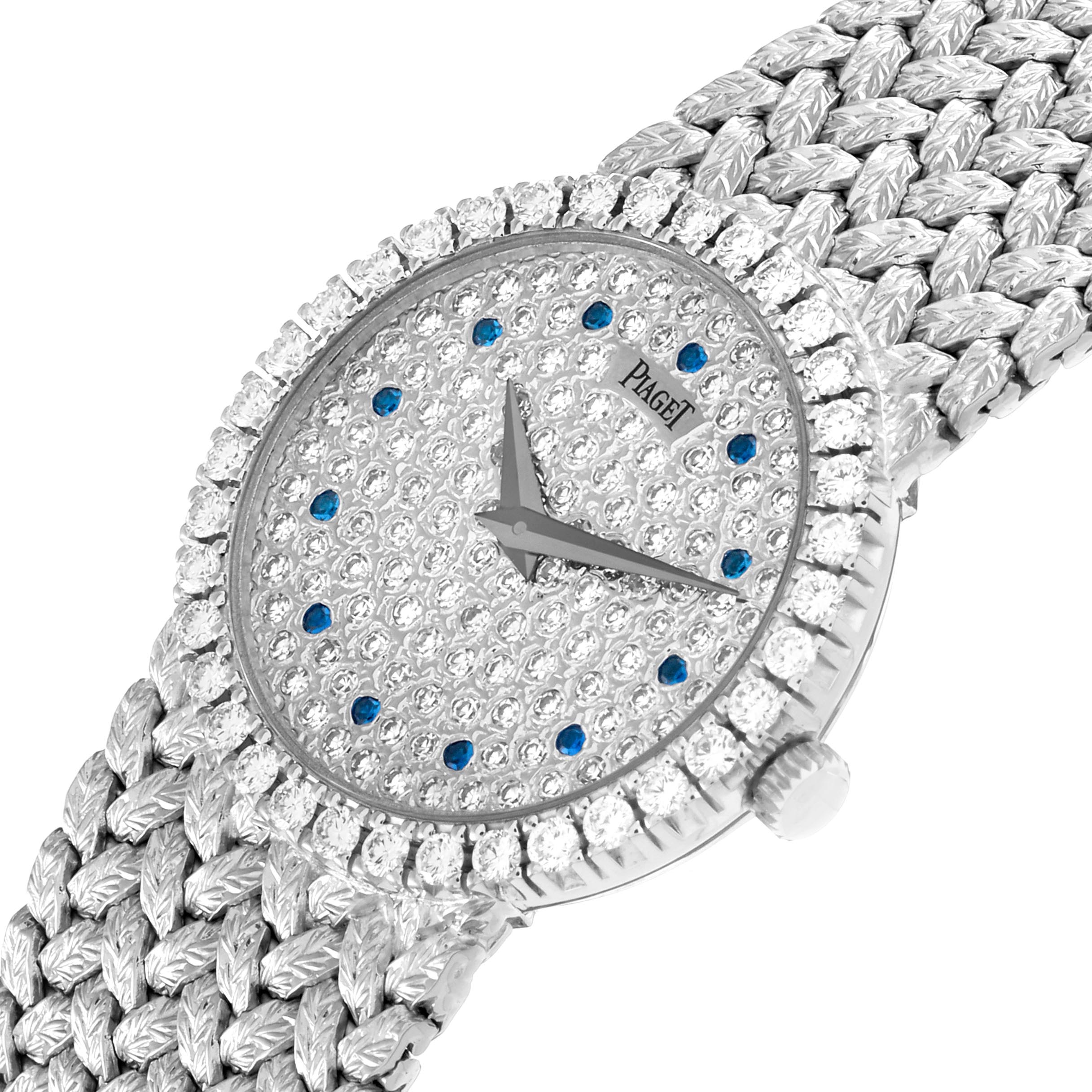 The Piaget 9706D2 Women
s White Gold Silver Dial 9706D2 Women
s White Gold Silver Dial Tradition model 9706D2 watch is shown at a slight angle, displaying its diamond-encrusted face, blue sapphire accents, and woven strap.
