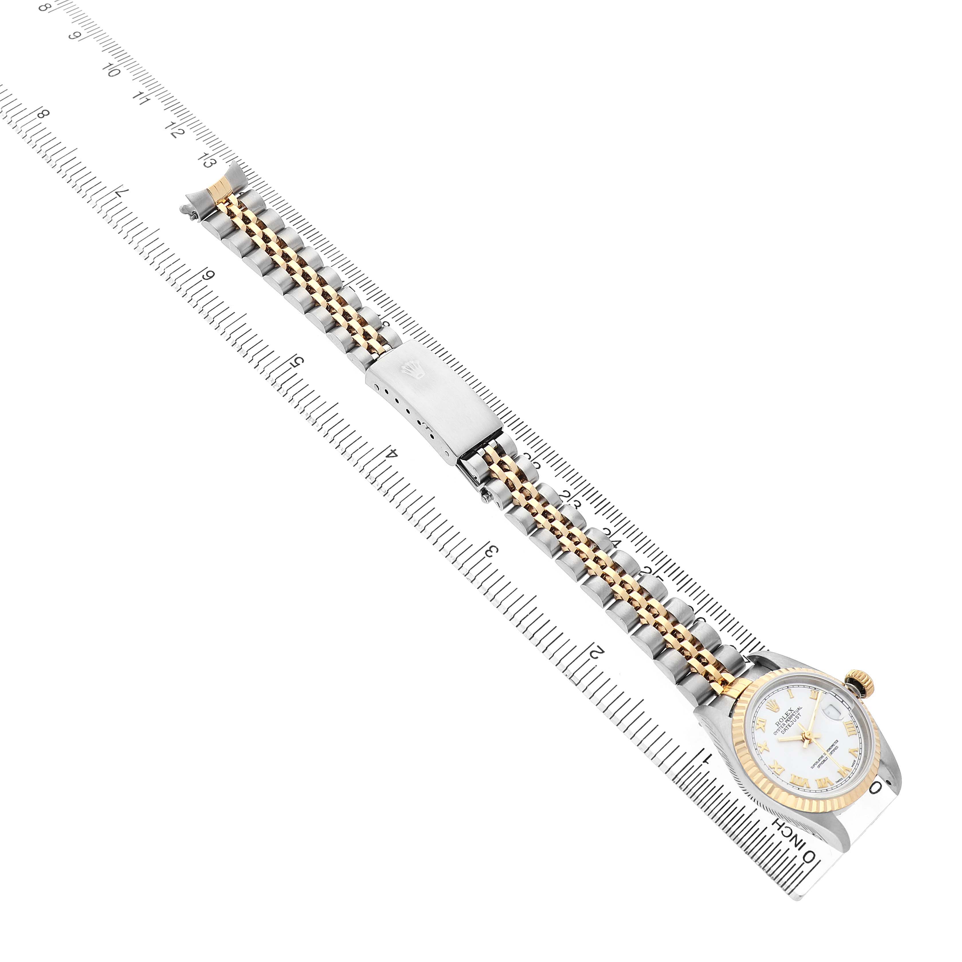The Rolex Datejust 79173 Women's Steel and Gold (two tone) White Dial watch is displayed diagonally, showing the face, bezel, and full bracelet laid along a ruler.