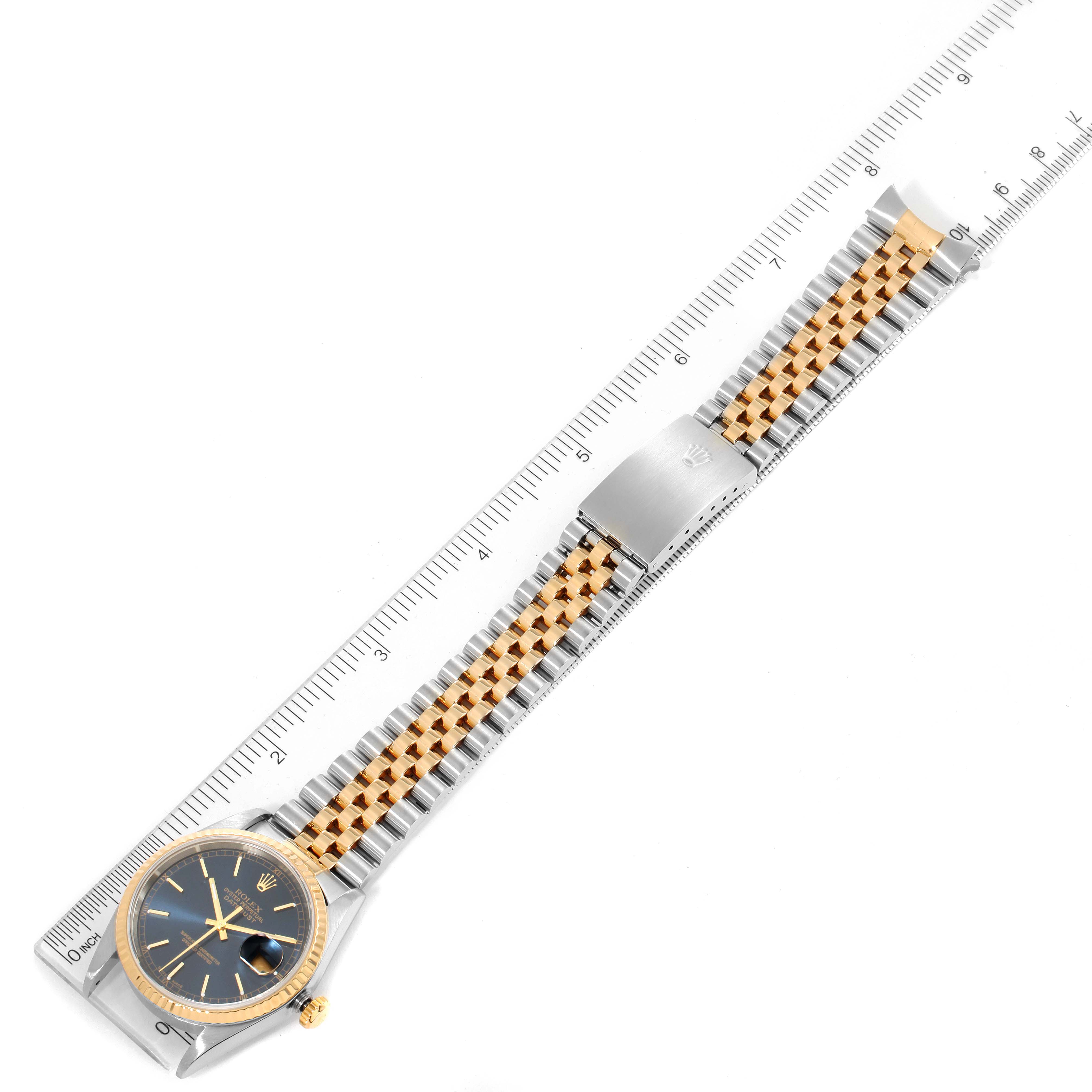 The Rolex Datejust 16233 Men's Steel and Gold (two tone) Blue Dial 16233 Men's Steel and Gold (two tone) Blue Dial watch is shown flat with its full bracelet and ruler for size reference.