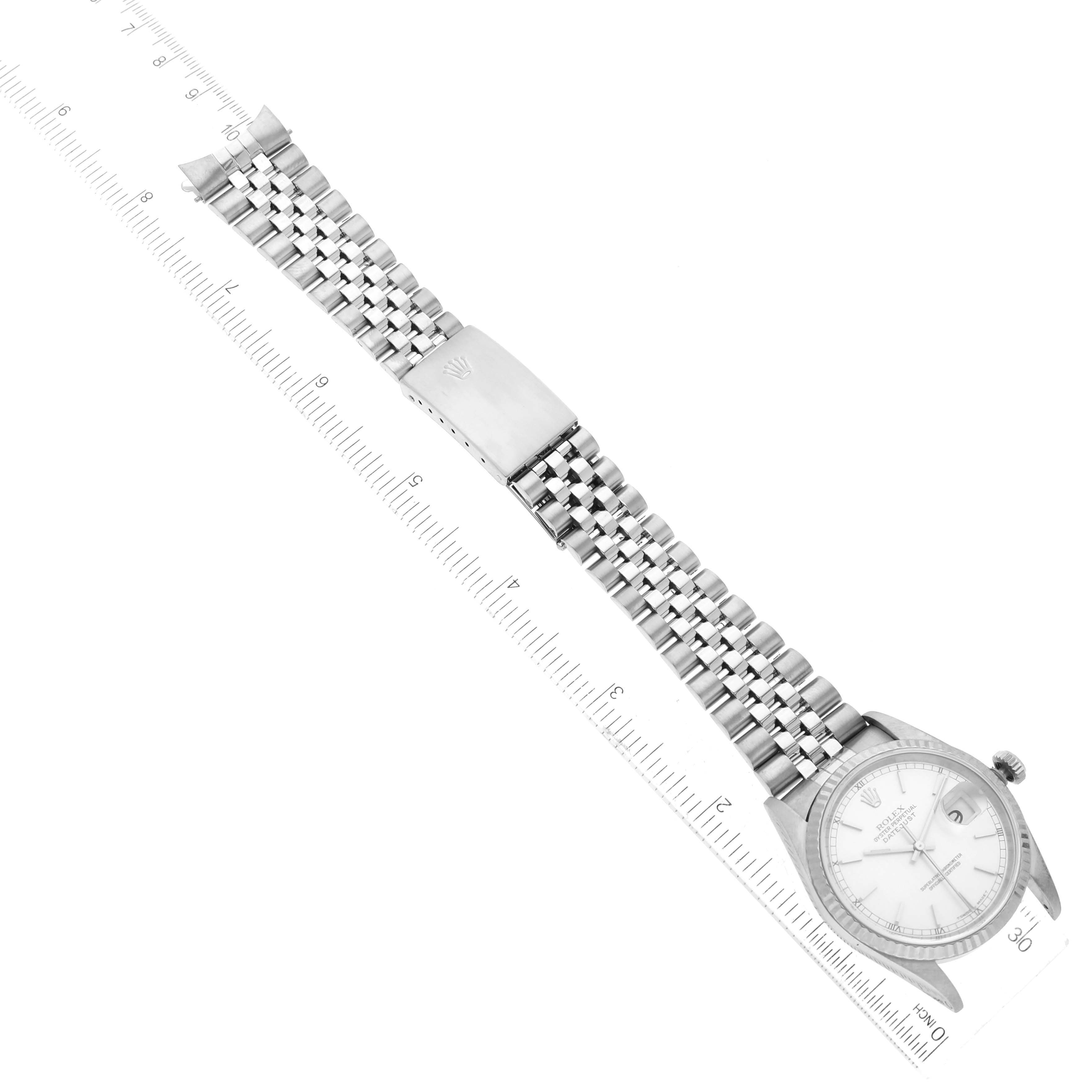 The image shows a Rolex Datejust 16234 Men's Stainless Steel Silver Dial 16234 Men's Stainless Steel Silver Dial watch laying flat, featuring its face, jubilee bracelet, and clasp, along with a ruler for scale.