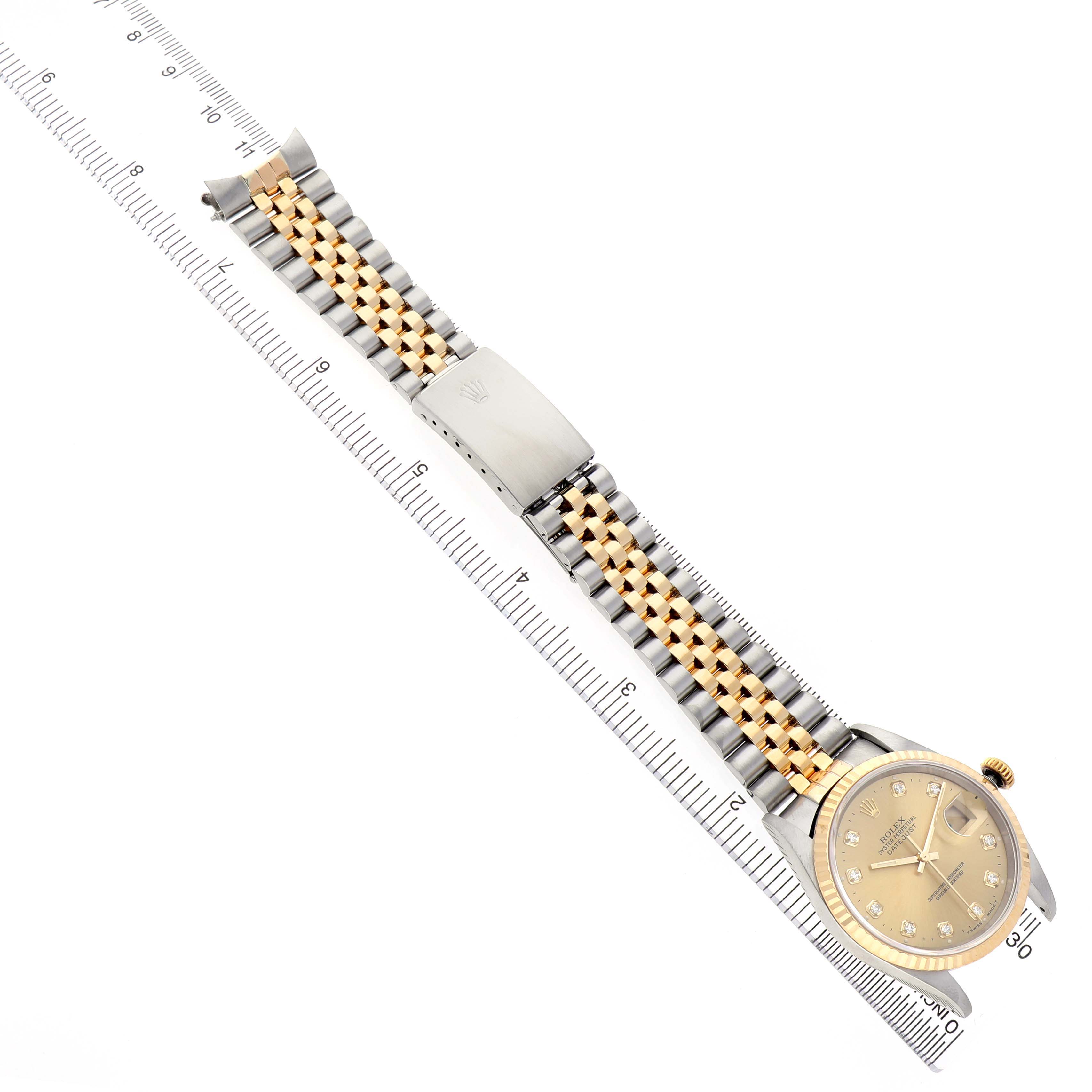 The Rolex Datejust 81443 Men's Steel and Gold (two tone) Champagne Dial is shown from an overhead angle, featuring the full bracelet, clasp, and dial alongside a ruler for scale.