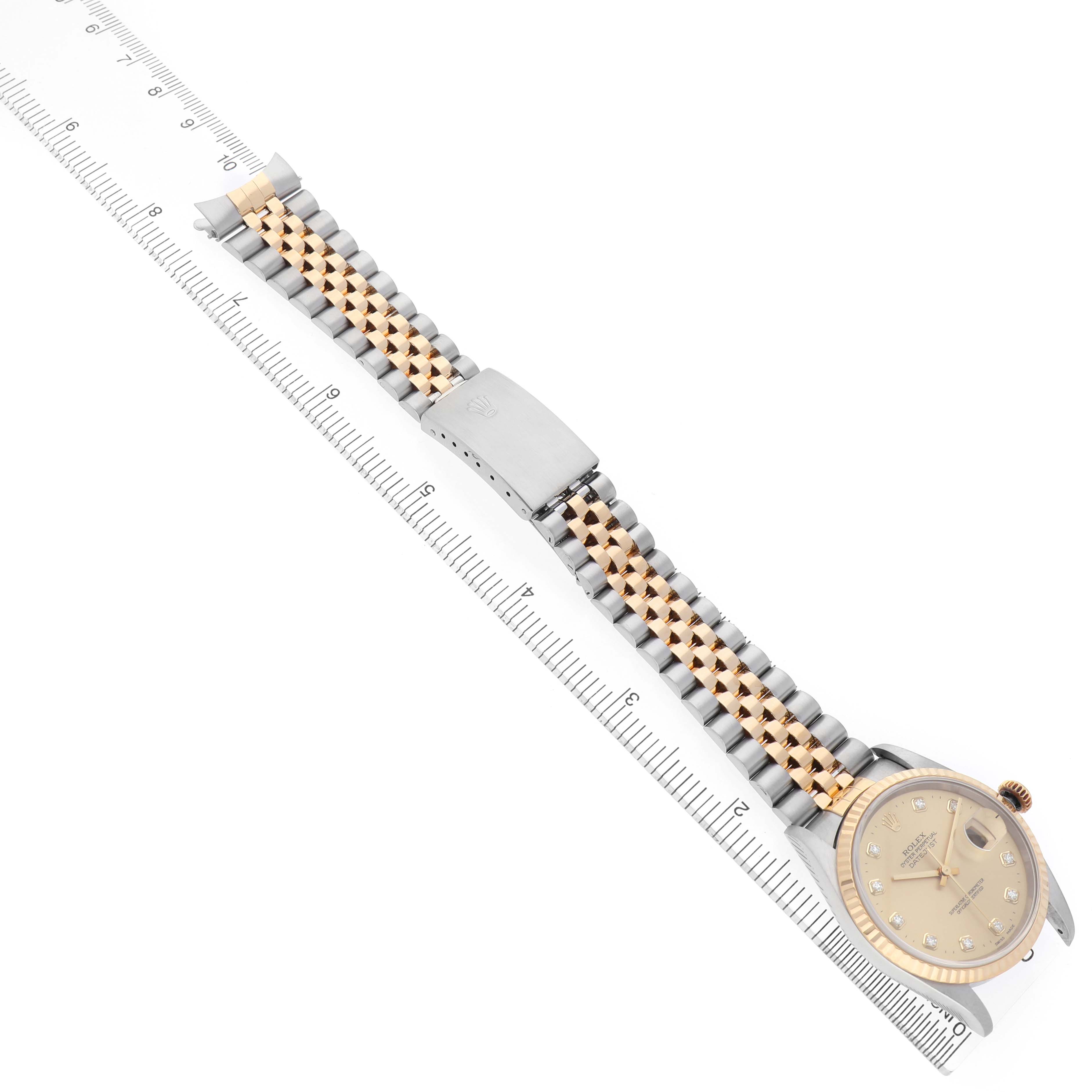 The Rolex Datejust 16233 Men's Steel and Gold (two tone) Champagne Dial is shown from a top-down angle, displaying the face, two-tone bracelet, clasp, and part of a ruler for scale.