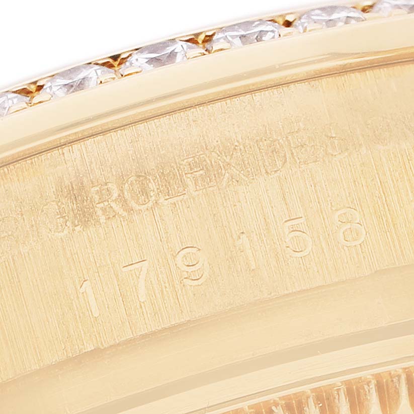 The image shows a close-up of the engraving on the side of a Rolex President 179158 Women's Yellow Gold Mother of Pearl Dial's case, revealing numbers and diamond-set bezel detail.