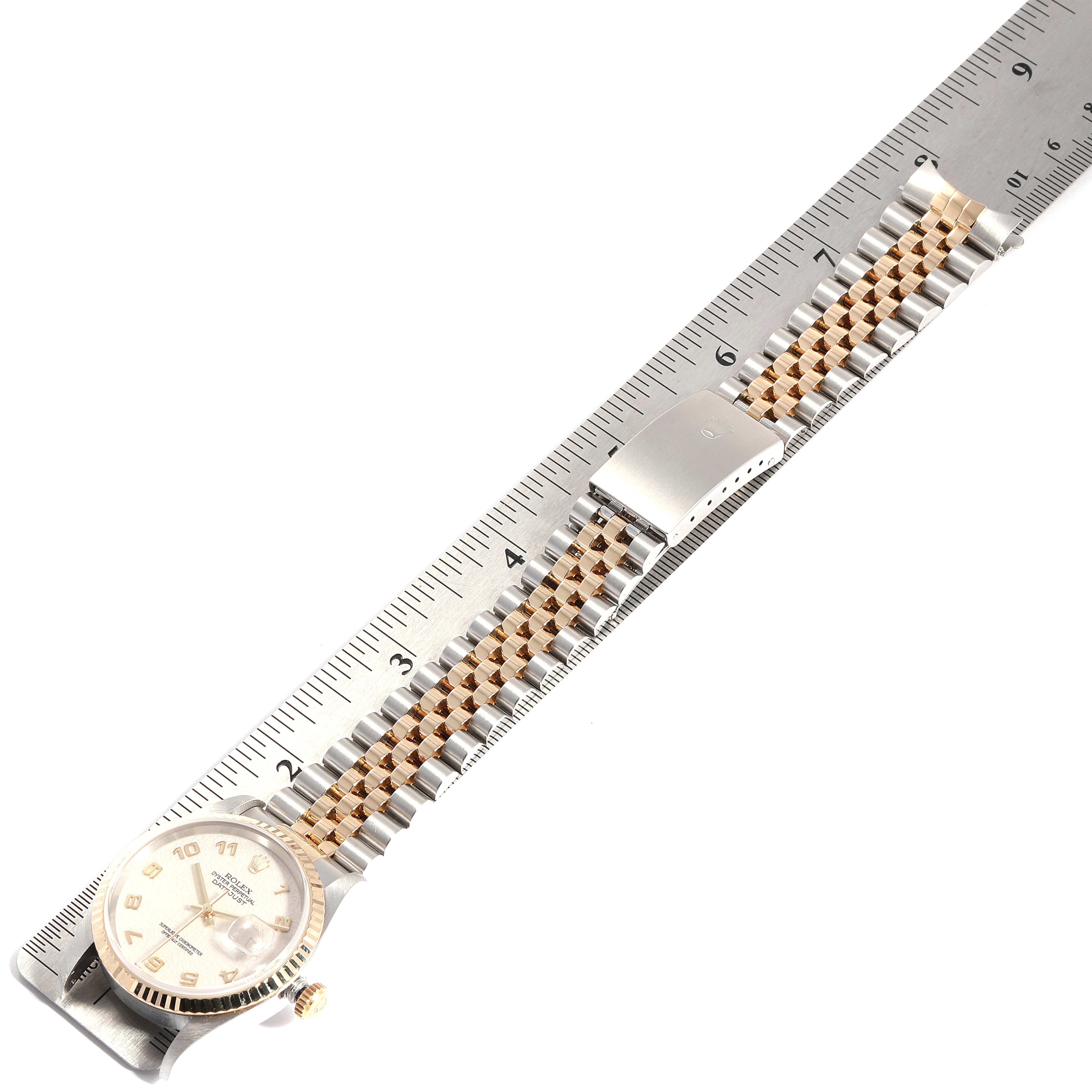 The Rolex Datejust 16233 Men's Steel and Gold (two tone) Beige Dial 16233 Men's Steel and Gold (two tone) Beige Dial watch is shown from a top-down angle, featuring the dial, bezel, bracelet, and clasp, next to a ruler for scale.