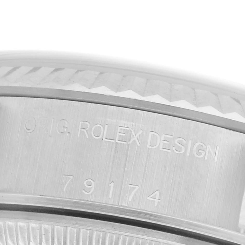 The image shows a close-up of the engraved case and fluted bezel of a Rolex Datejust 79174 Women
s Stainless Steel White Dial 79174 Women
s Stainless Steel White Dial watch.