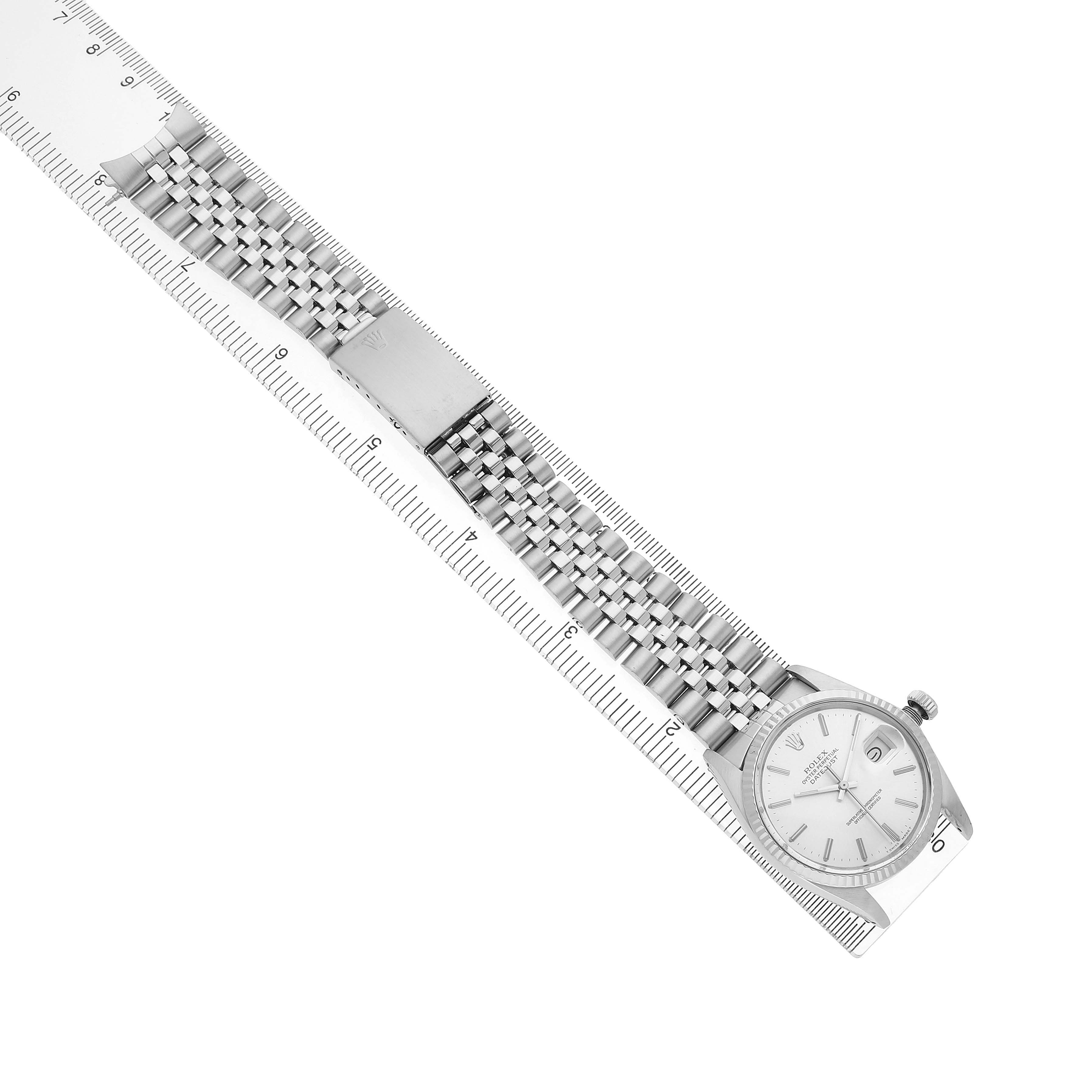 The image shows a Rolex Datejust 16014 Men's Stainless Steel Silver Dial watch at an overhead angle with a full view of the dial, bracelet, and clasp alongside a ruler.
