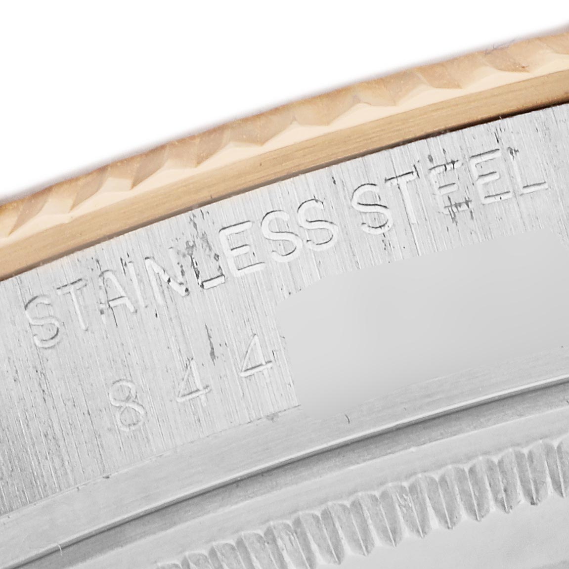 The image shows a close-up of the Rolex Datejust 16013 Men
s Steel and Gold (two tone) Champagne Dial 16013 Men
s Steel and Gold (two tone) Champagne Dial watch
s bezeling and engraving on the case edge, highlighting "STAINLESS STEEL."