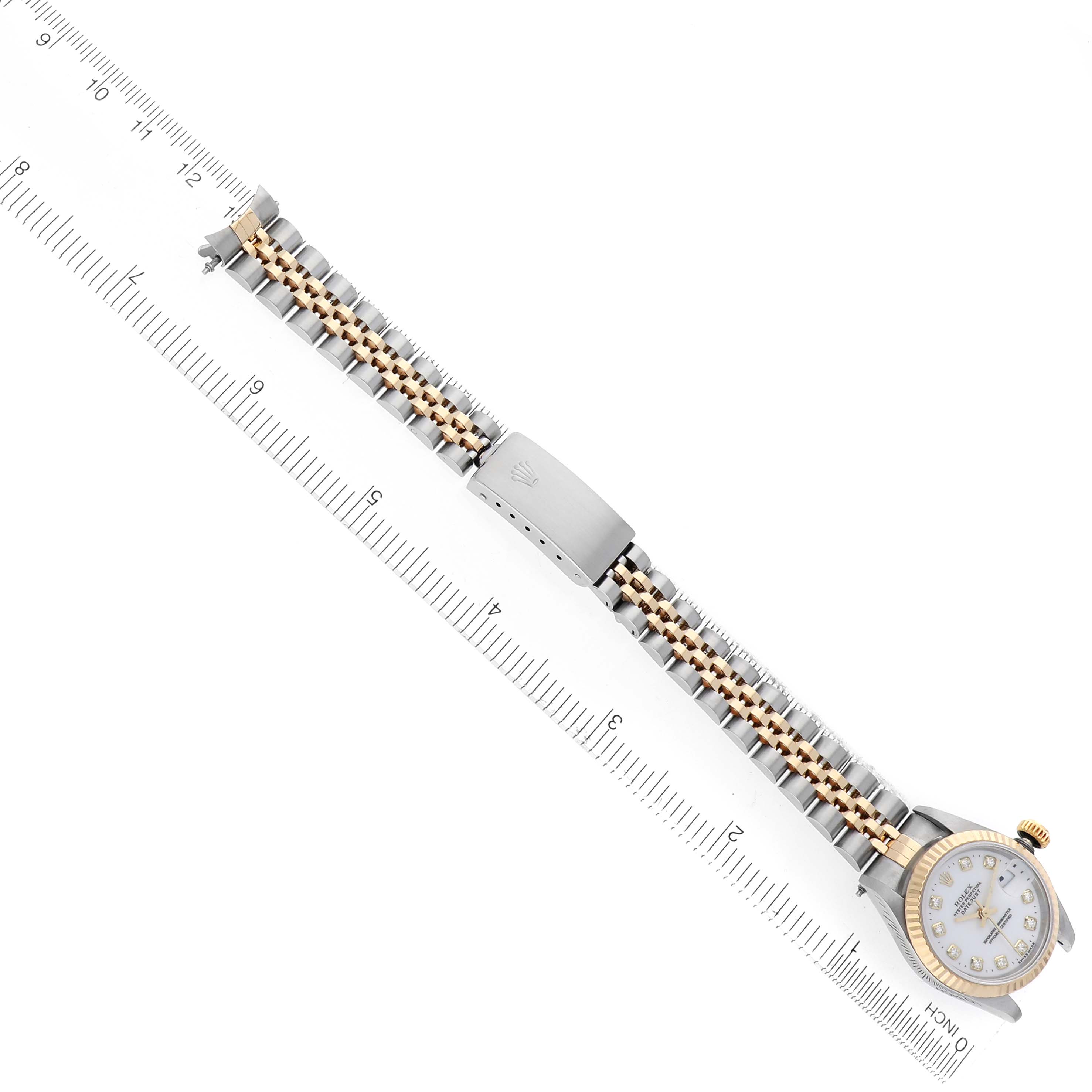 The image shows the Rolex Datejust 69173 Women
s Steel and Gold (two tone) White Dial 69173 Women
s Steel and Gold (two tone) White Dial watch at an angle displaying the full bracelet and clasp alongside a ruler for scale.