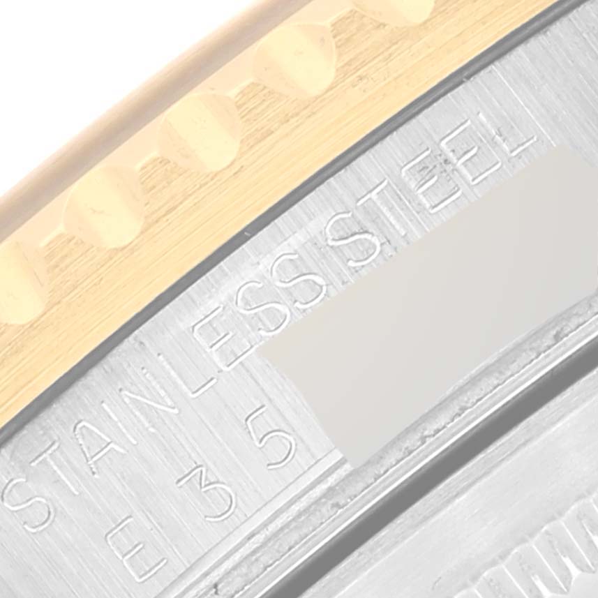 This is a close-up of the Rolex GMT-Master 16713 Men's Steel and Gold (two tone) Brown Dial 16713 Men's Steel and Gold (two tone) Brown Dial's bezel with partial engraving visible on its stainless steel side.