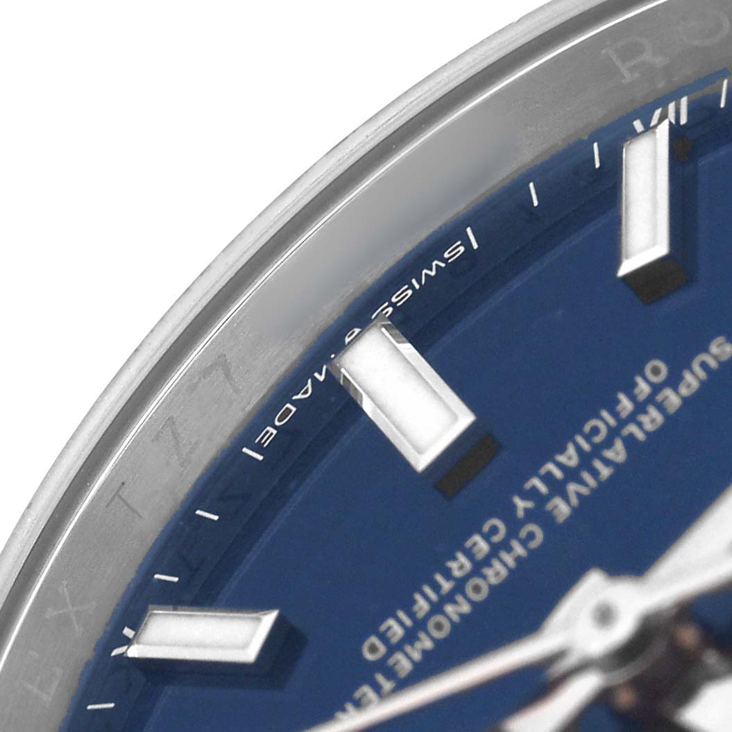 The image shows a close-up of the Rolex Oyster Perpetual 124200 Men's Stainless Steel Blue Dial watch face, highlighting the bezel, part of the dial, and hour markers.