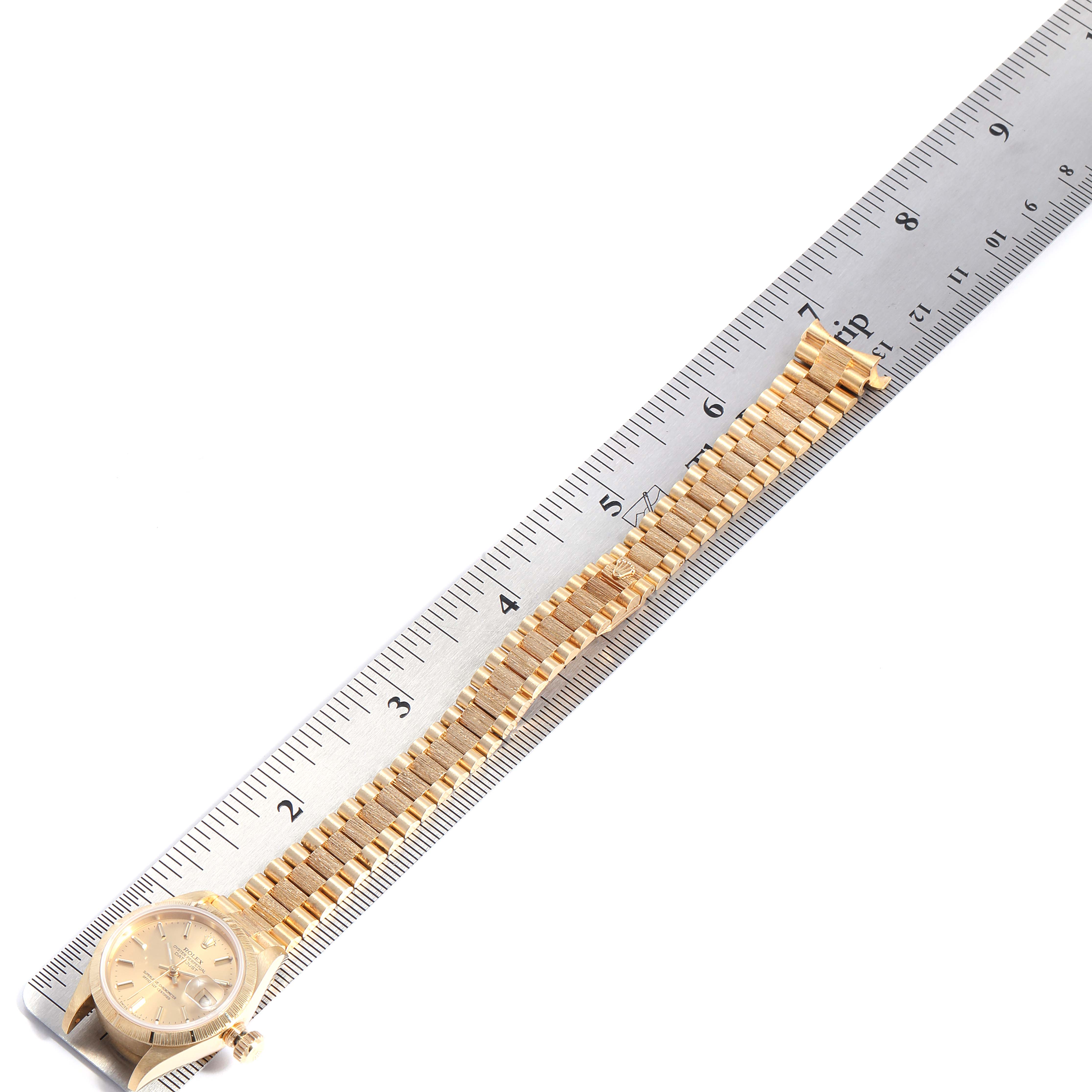 The image shows a Rolex President 69278 Women
s Yellow Gold Champagne Dial 69278 Women
s Yellow Gold Champagne Dial model watch with a gold bracelet, next to a ruler measuring its length.