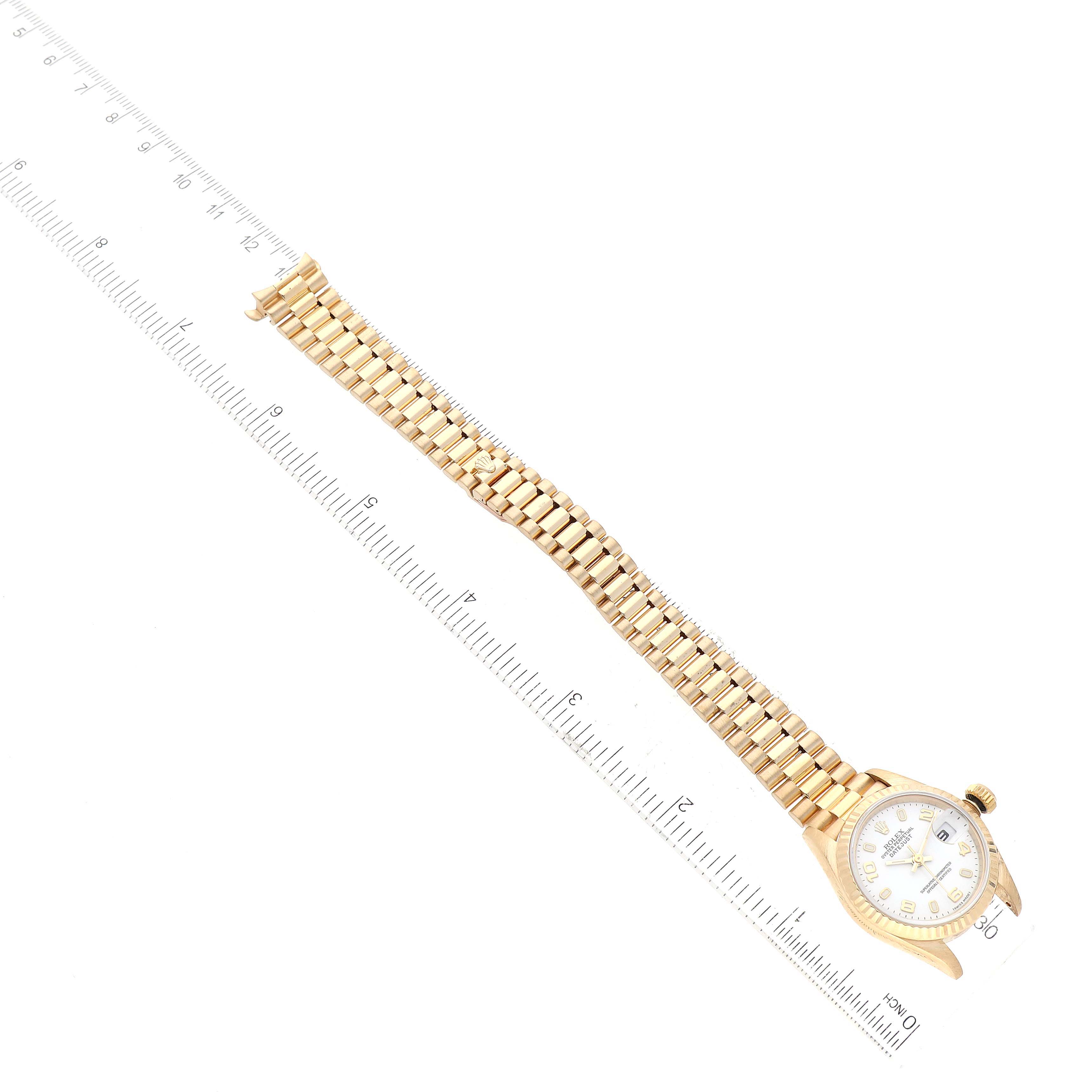 The Rolex President 69178 Women's Yellow Gold White Dial 69178 Women's Yellow Gold White Dial model watch is shown from a top-down angle, fully extended with a ruler for scale.