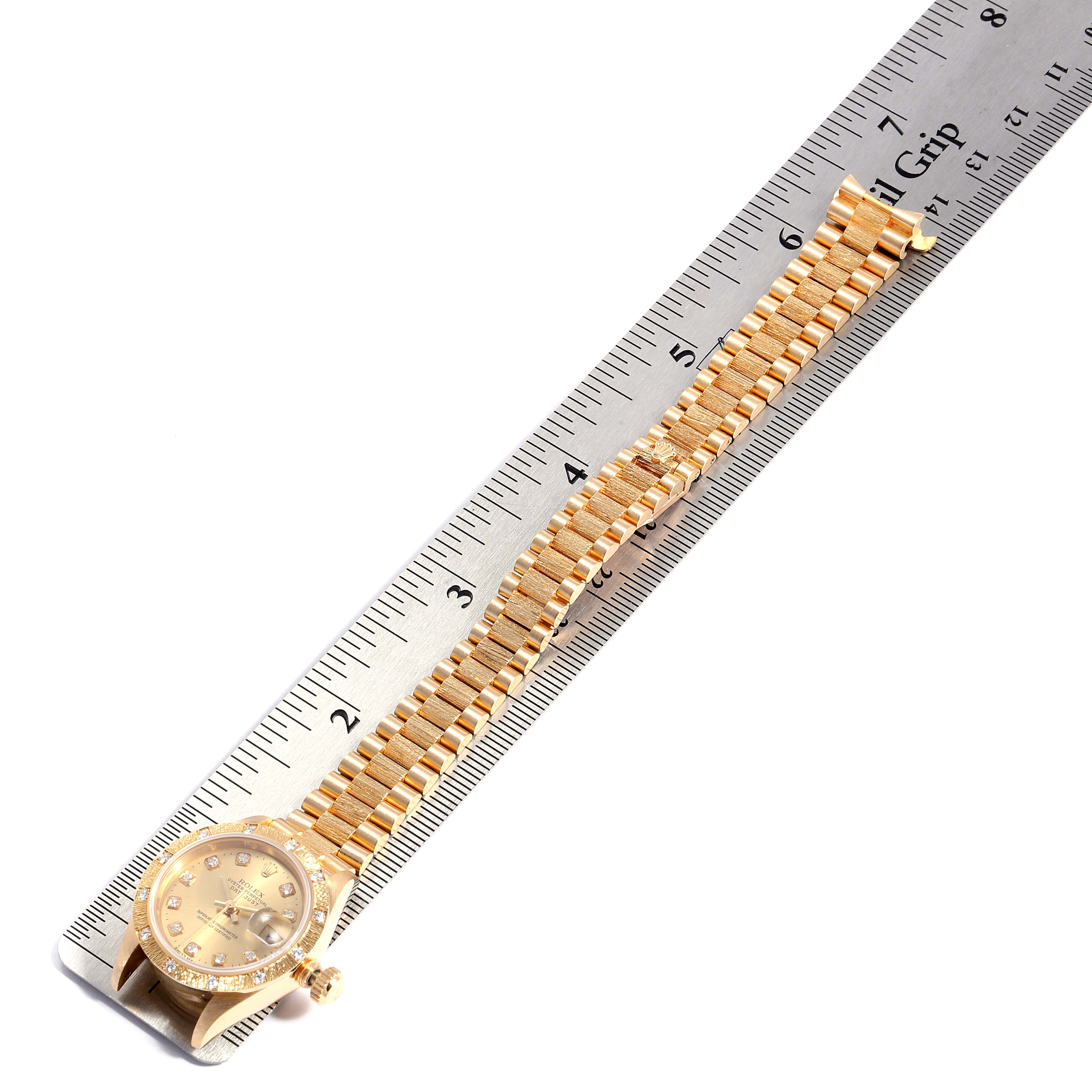 The image shows a top-down view of a gold Rolex President 69288 Women
s Yellow Gold Champagne Dial 69288 Women
s Yellow Gold Champagne Dial watch lying along a ruler, displaying both the dial and the bracelet.