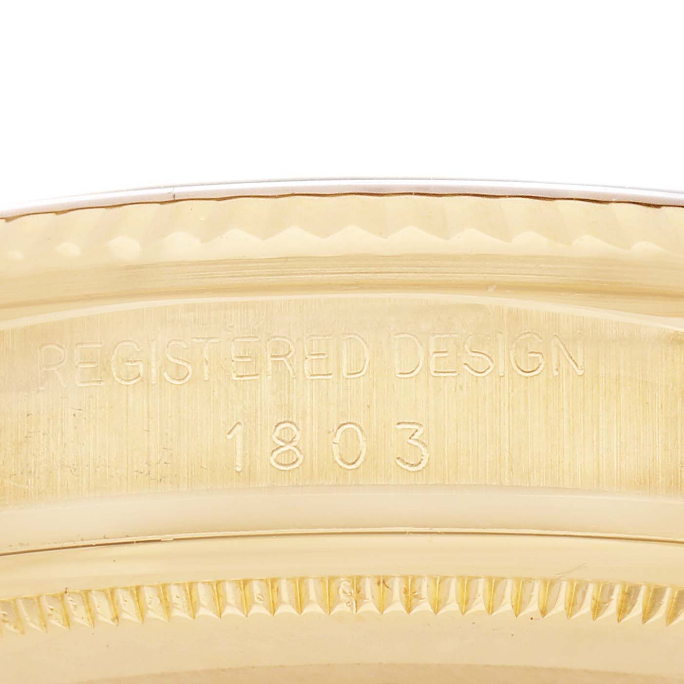 The image shows a close-up of the engraved side of a Rolex President 1803 Men
s Yellow Gold Champagne Dial 1803 Men
s Yellow Gold Champagne Dial watch case, highlighting the "REGISTERED DESIGN" and model number "1803."