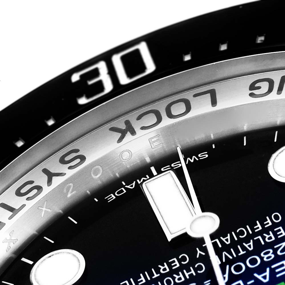 The image shows a close-up angle of the Rolex Sea-Dweller 116660 Men
s Stainless Steel Blue Dial 116660 Men
s Stainless Steel Blue Dial
s bezel, dial with text, and part of an hour marker.