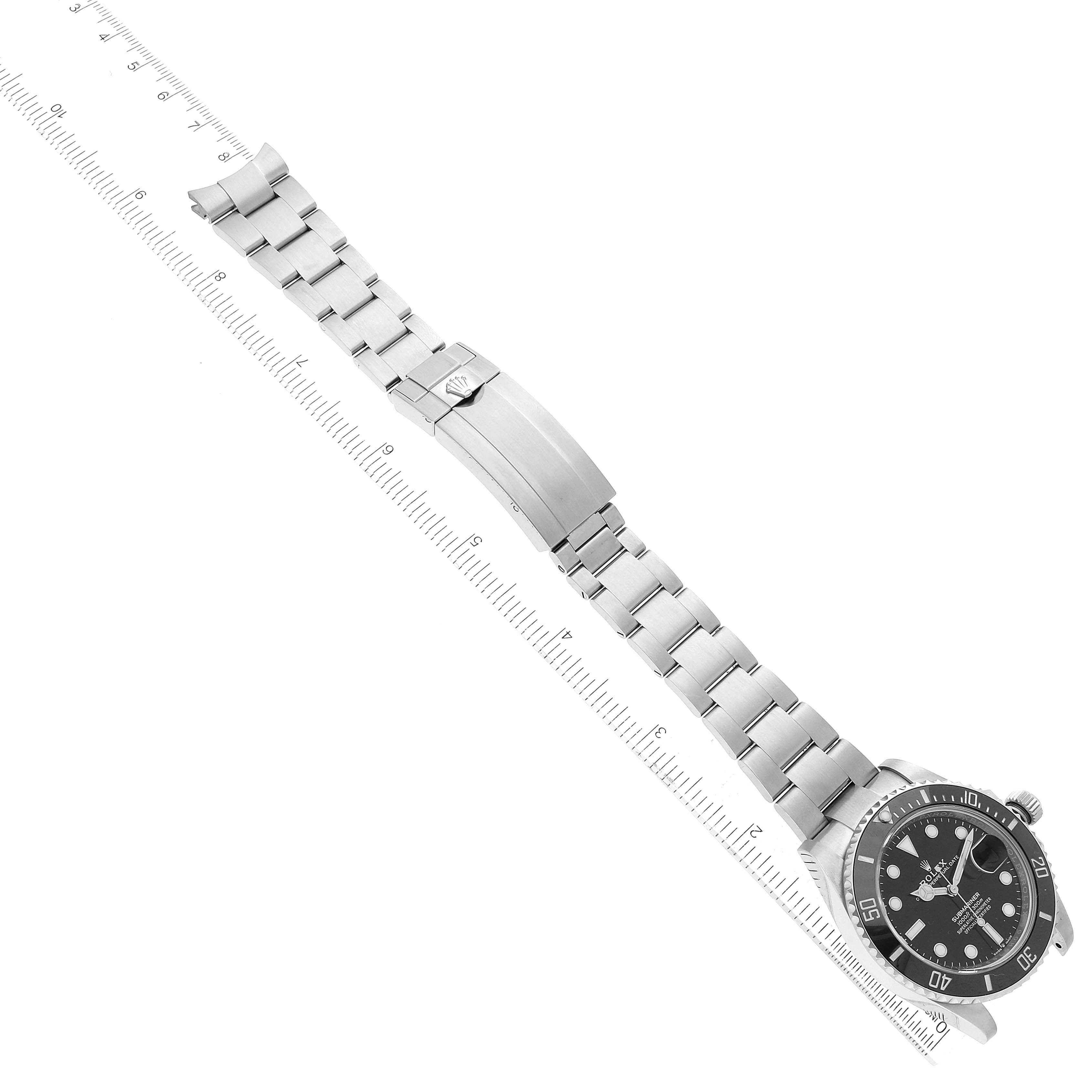 The Rolex Submariner 126610 Men's Stainless Steel Black Dial watch is shown from an angled top view, displaying the full case, bezel, and bracelet alongside a ruler for scale.
