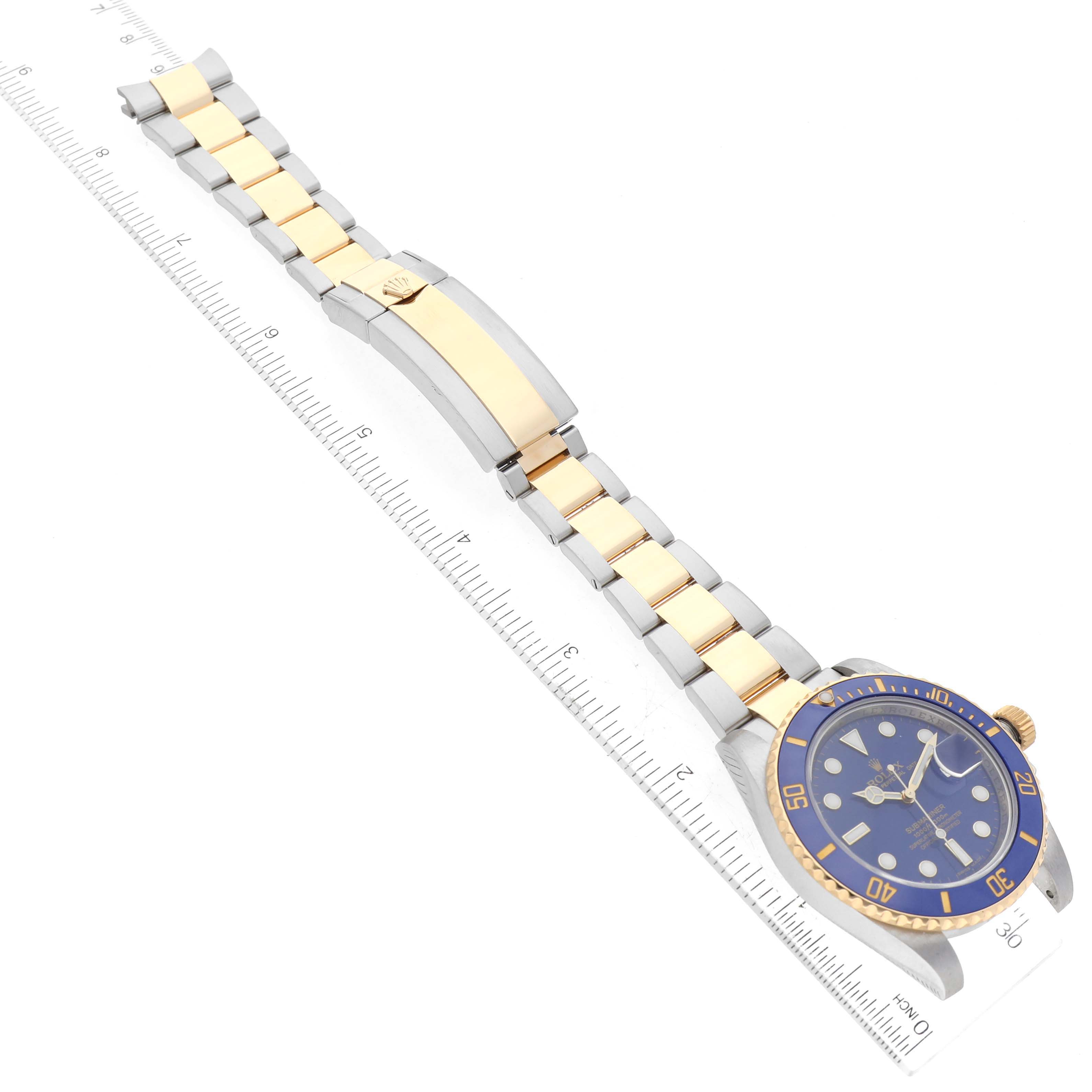 The image shows a Rolex Submariner 116613LB Men's Steel and Gold (two tone) Blue Dial 116613LB Men's Steel and Gold (two tone) Blue Dial watch laid flat, featuring its bracelet, clasp, and blue dial with a ruler for scale.