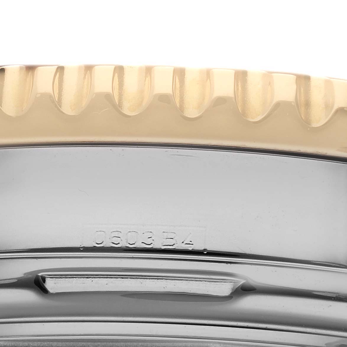 The image shows a close-up side view of the bezel and part of the case of a Breitling Navitimer D23322 Men
s Steel and Gold (two tone) Black Dial D23322 Men
s Steel and Gold (two tone) Black Dial watch, including some engraved details.