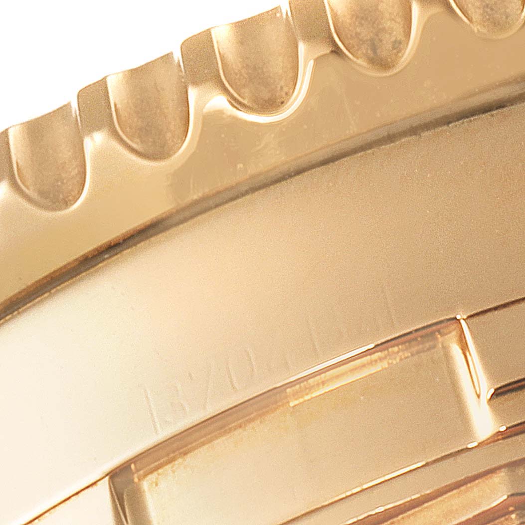 The image shows a close-up of the gold bezel and case of a Breitling Navitimer K24322 Men's Yellow Gold Black Dial K24322 Men's Yellow Gold Black Dial watch.