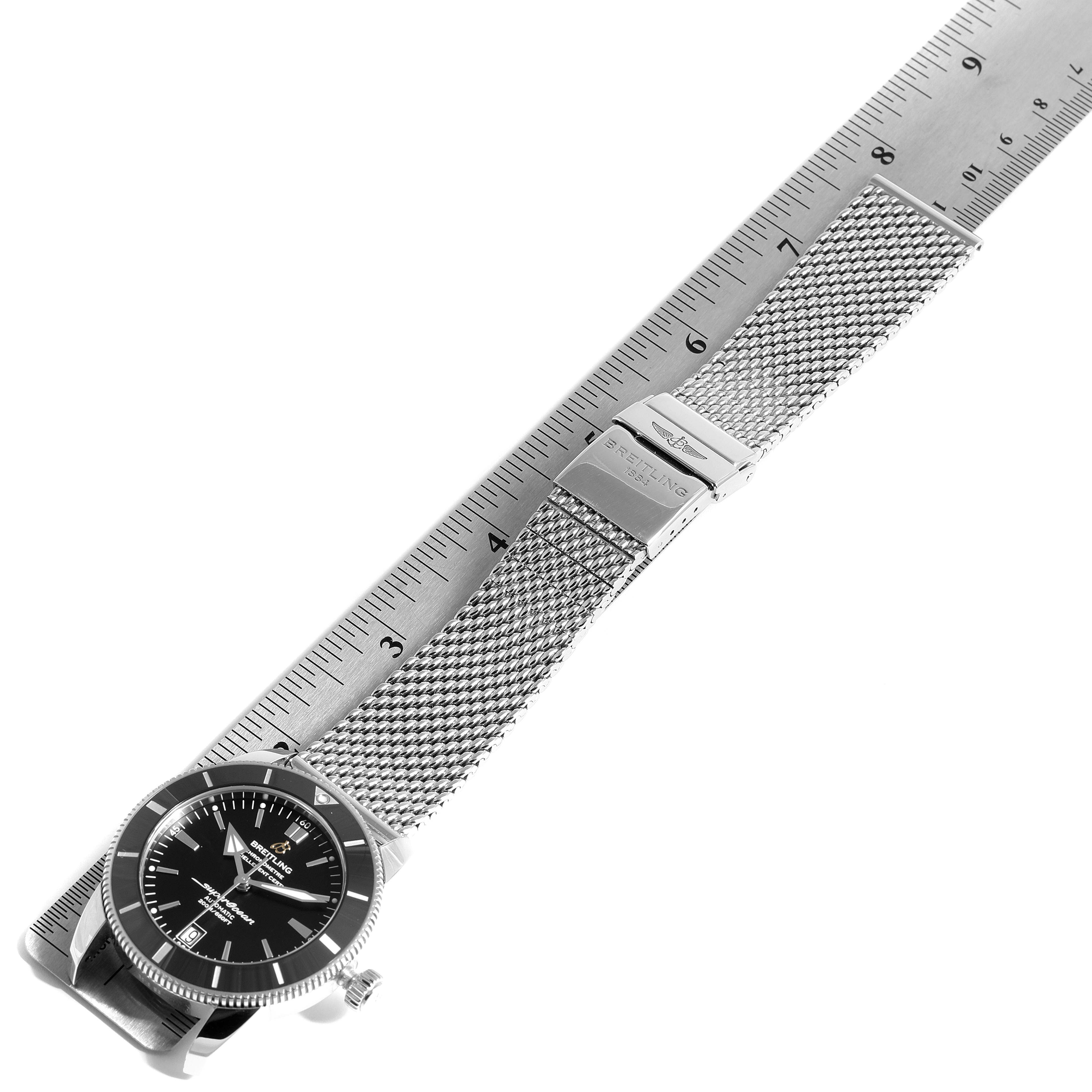 The Breitling Superocean AB2010161C1A1 Men
s Stainless Steel Black Dial AB2010161C1A1 Men
s Stainless Steel Black Dial watch is displayed flat, showing the face, bezel, and metal mesh strap next to a ruler for scale.