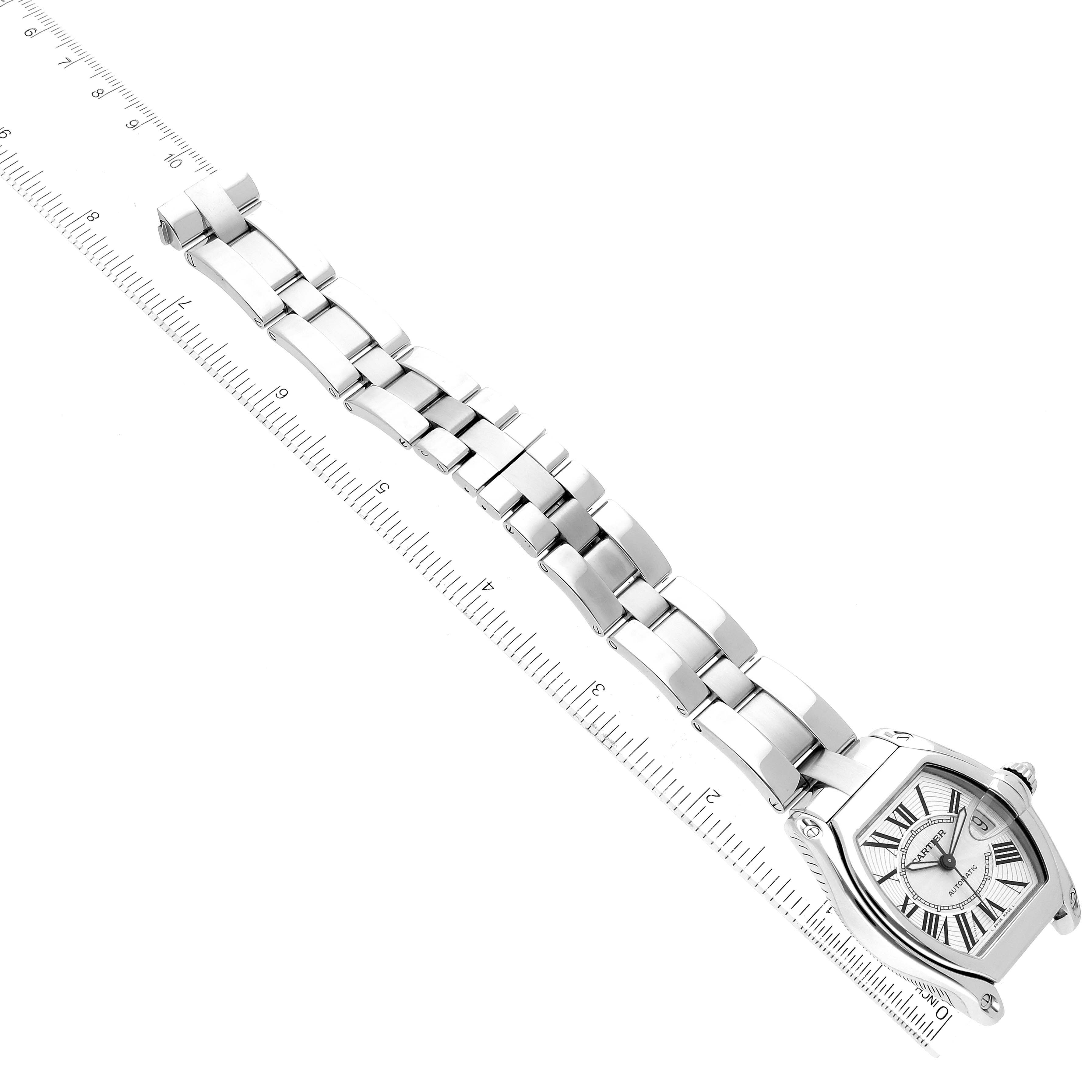 The Cartier Roadster W62025V3 Men's Stainless Steel Silver Dial W62025V3 Men's Stainless Steel Silver Dial watch is shown from a top-down angle, displaying its face and metal bracelet beside a measuring ruler.