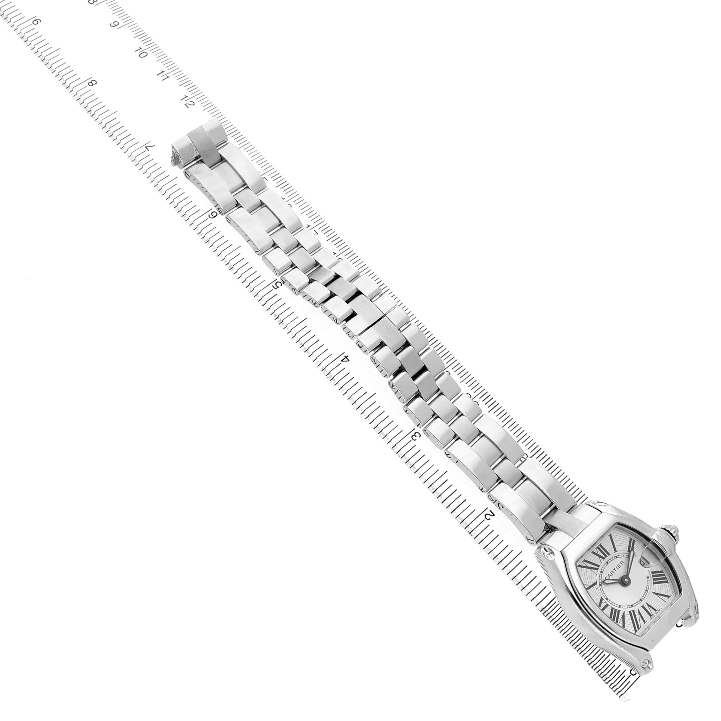 This image shows a Cartier Roadster W62016V3 Women's Stainless Steel Silver Dial watch at an angle displaying its face and full stainless steel bracelet, set diagonally against a ruler.