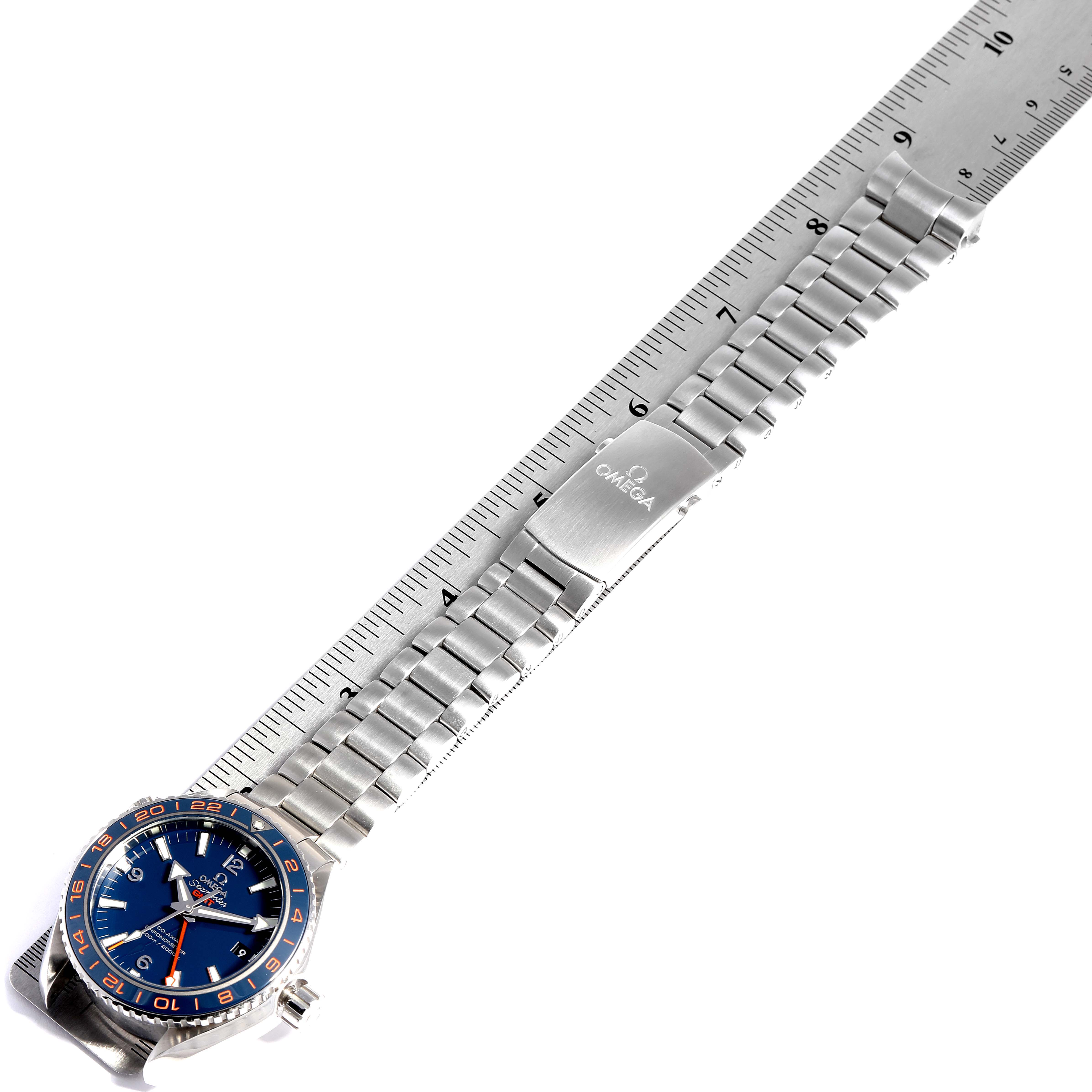 The image shows an Omega Planet Ocean 232.30.44.22.03.001 Men
s Stainless Steel Blue Dial 232.30.44.22.03.001 Men
s Stainless Steel Blue Dial watch from a top-down angle, featuring the dial, bezel, bracelet, and clasp alongside a ruler.