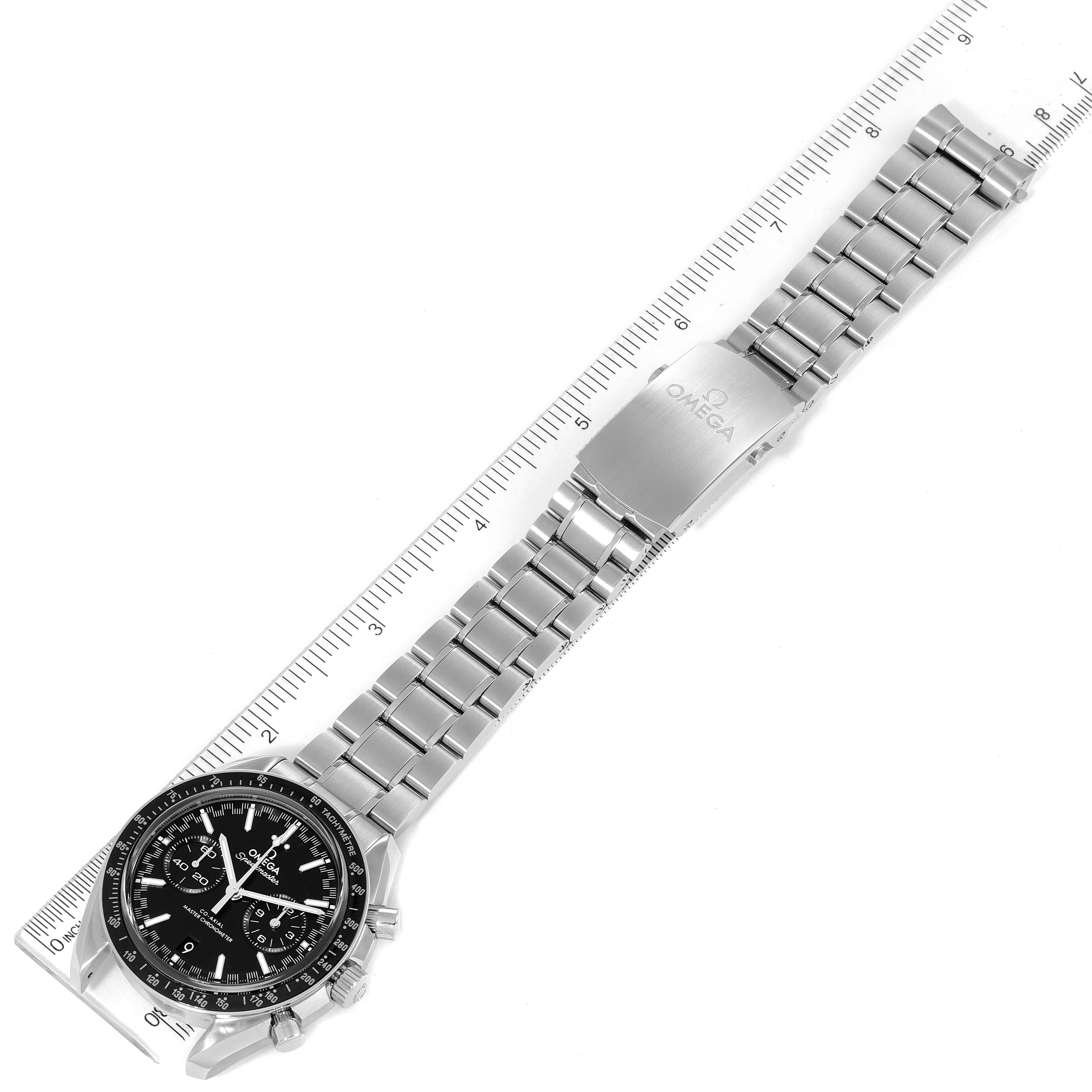 The image shows the Omega Speedmaster 329.30.44.51.01.001 Men
s Stainless Steel Black Dial 329.30.44.51.01.001 Men
s Stainless Steel Black Dial watch laid flat, displayed with a metal bracelet and clasp alongside a ruler.