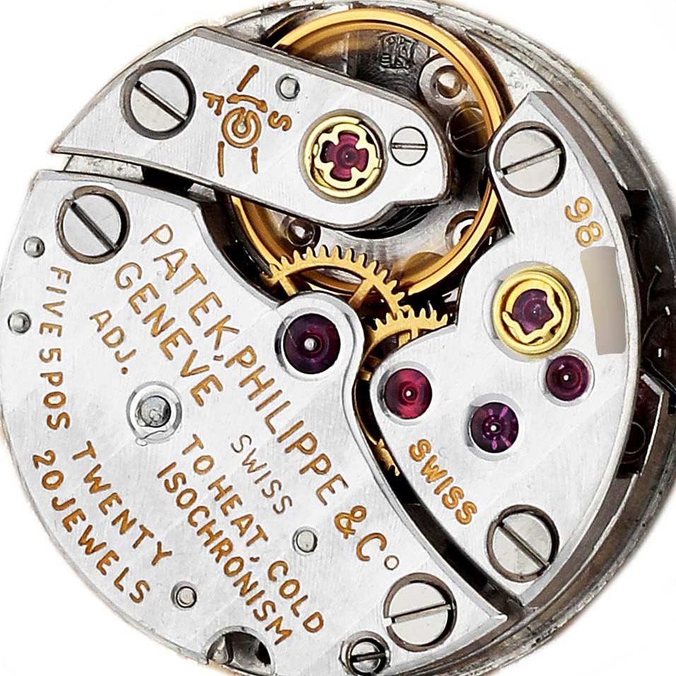 The image shows the movement of a Patek Philippe Golden Ellipse 3350 Women
s White Gold Silver Dial 3350 Women
s White Gold Silver Dial watch, highlighting gears, jewels, and engravings from a top-down angle.