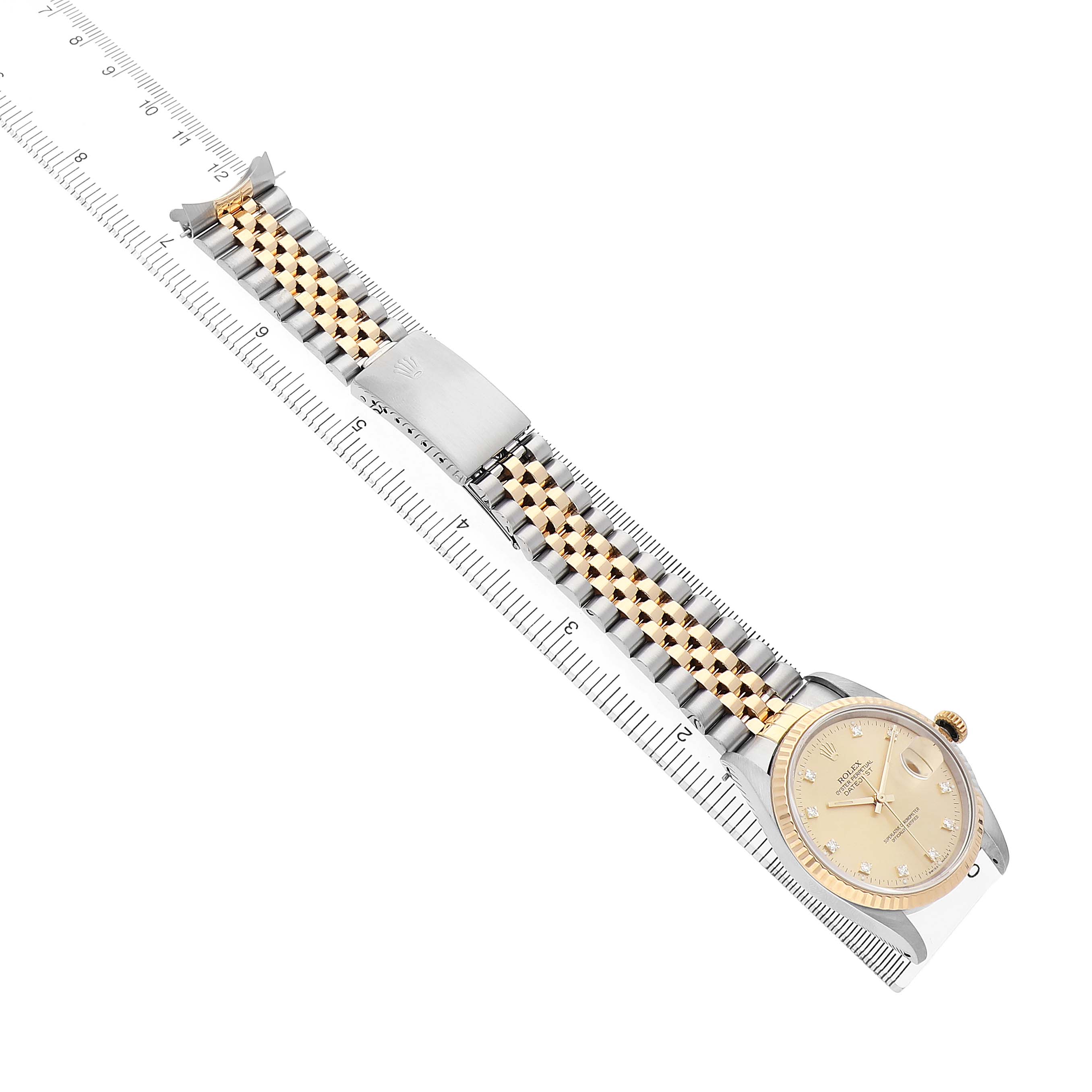 The Rolex Datejust 16233 Men's Steel and Gold (two tone) Champagne Dial watch is shown from an angled side view, displaying the face, bezel, and two-tone bracelet against a ruler.