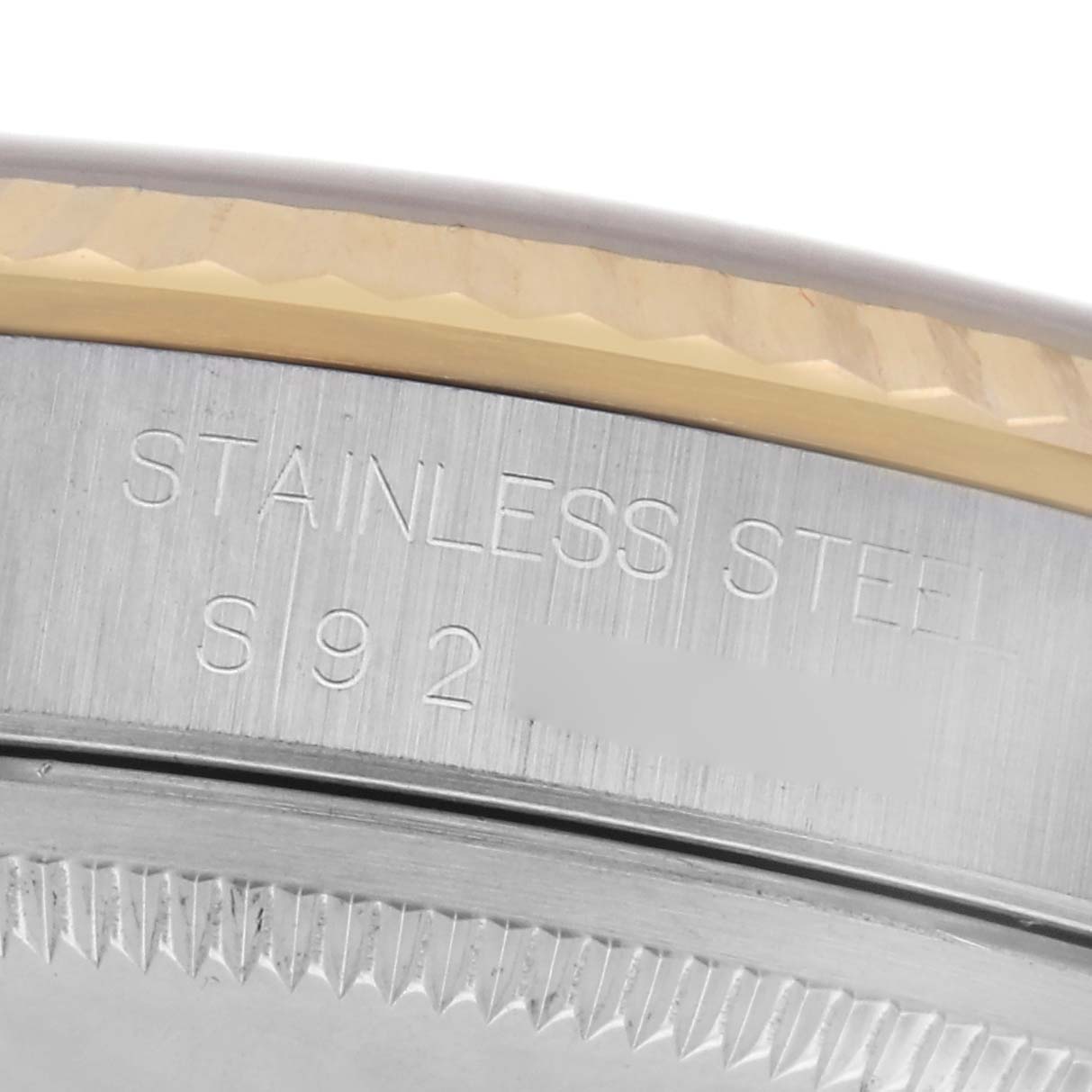 The image shows a close-up of the side of the Rolex Datejust 16233 Men's Steel and Gold (two tone) Champagne Dial 16233 Men's Steel and Gold (two tone) Champagne Dial case, highlighting the stainless steel engraving and part of the fluted bezel.