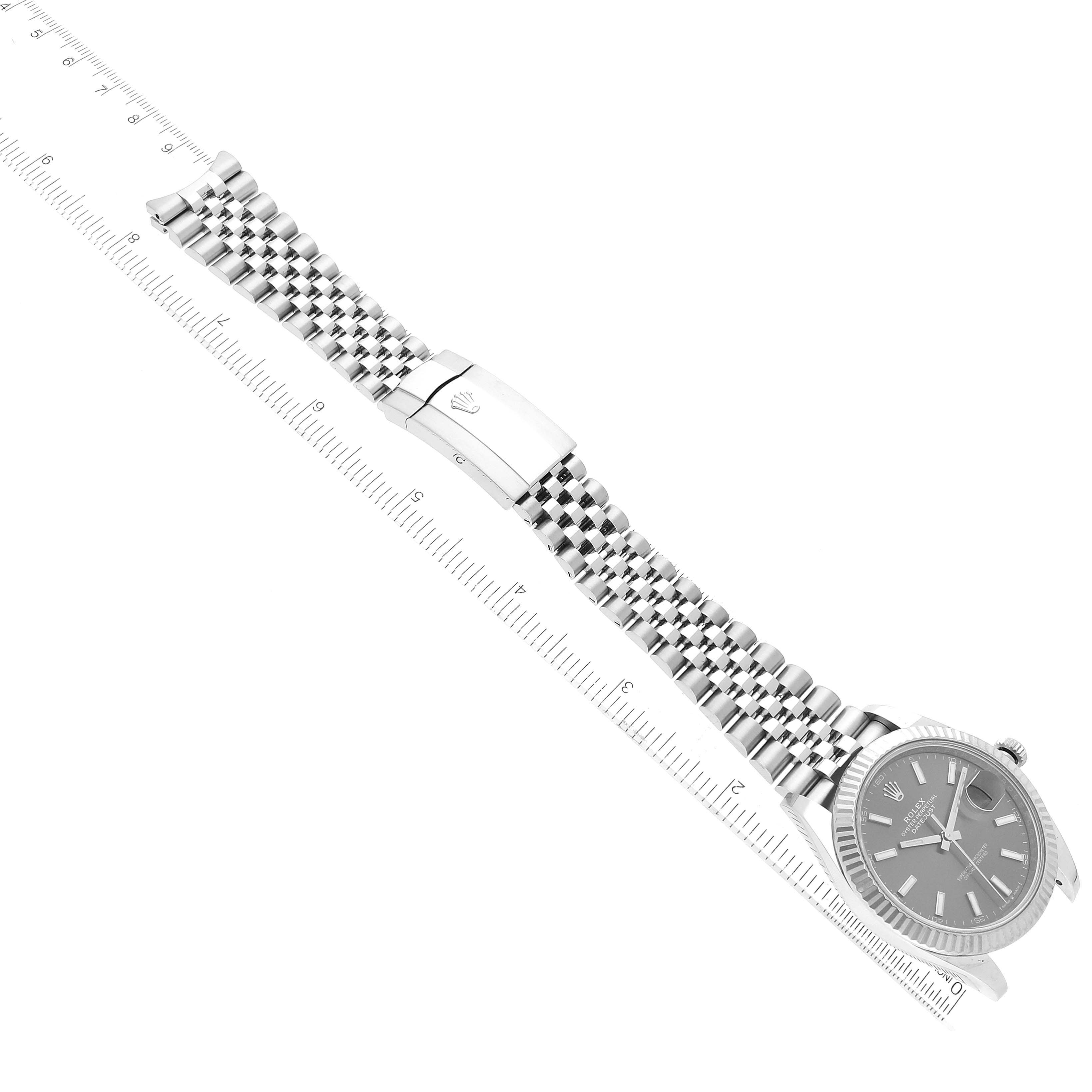 The image shows a Rolex Datejust 41 126334 Men
s Stainless Steel Grey Dial 126334 Men
s Stainless Steel Grey Dial watch with a Jubilee bracelet, a fluted bezel, and a grey dial, placed alongside a ruler for scale.