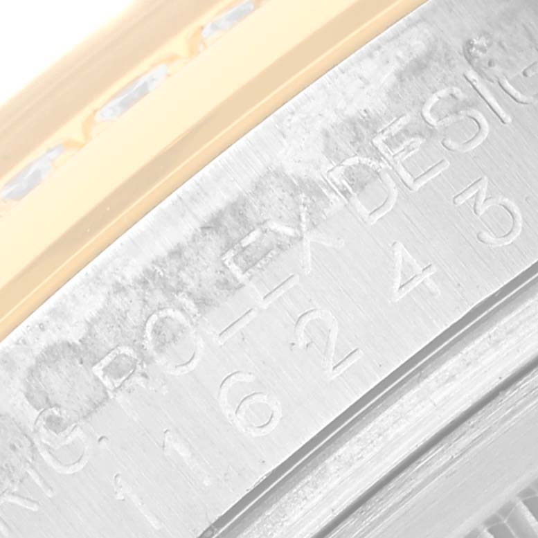 This close-up image of a Rolex Datejust 116243 Men's Steel and Gold (two tone) Champagne Dial 116243 Men's Steel and Gold (two tone) Champagne Dial watch shows its engraved inner bezel, showcasing the brand and part of the serial number.