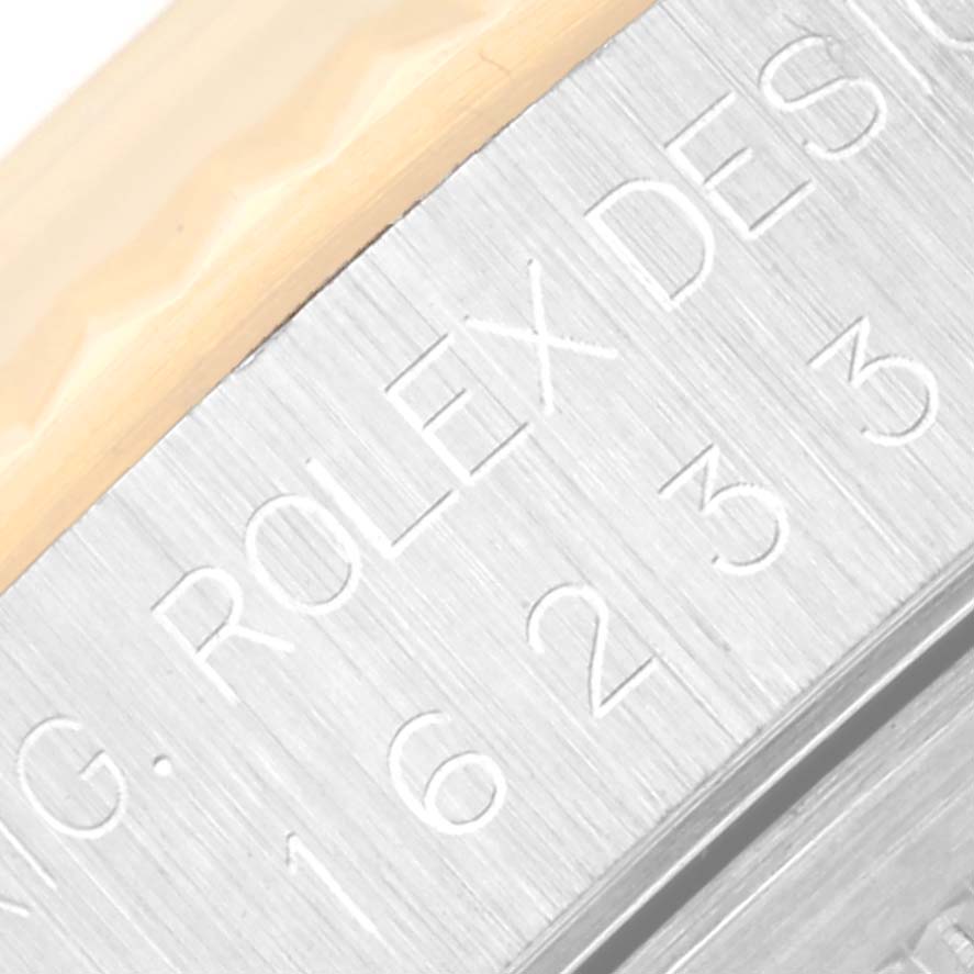 The image shows a close-up of the engraved side of a Rolex Datejust 16233 Men
s Steel and Gold (two tone) White Dial 16233 Men
s Steel and Gold (two tone) White Dial watch, highlighting part of the bezel and case.