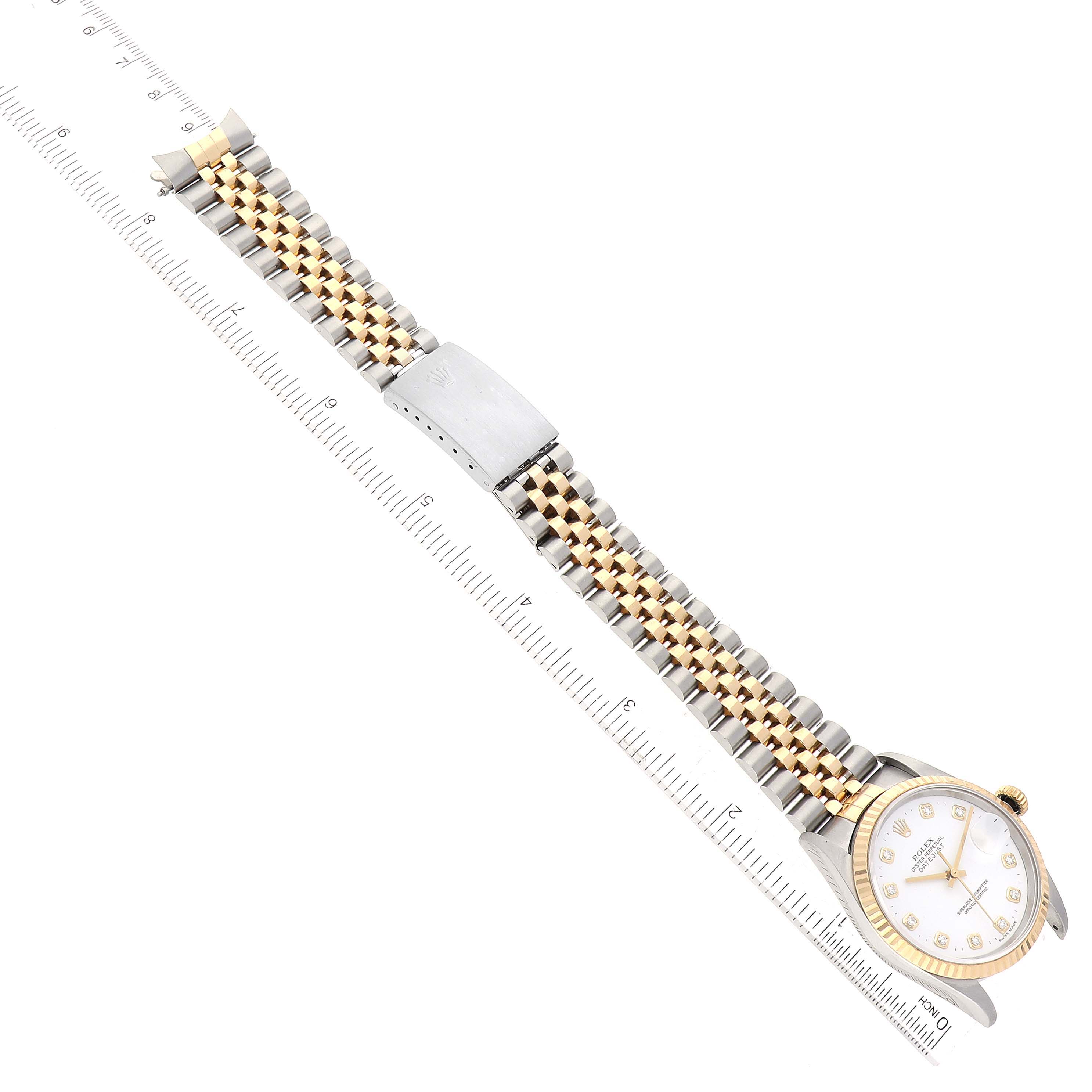 This image shows a Rolex Datejust 16233 Men's Steel and Gold (two tone) White Dial 16233 Men's Steel and Gold (two tone) White Dial watch laid flat with its two-tone bracelet and the face visible, alongside a ruler for measurement.