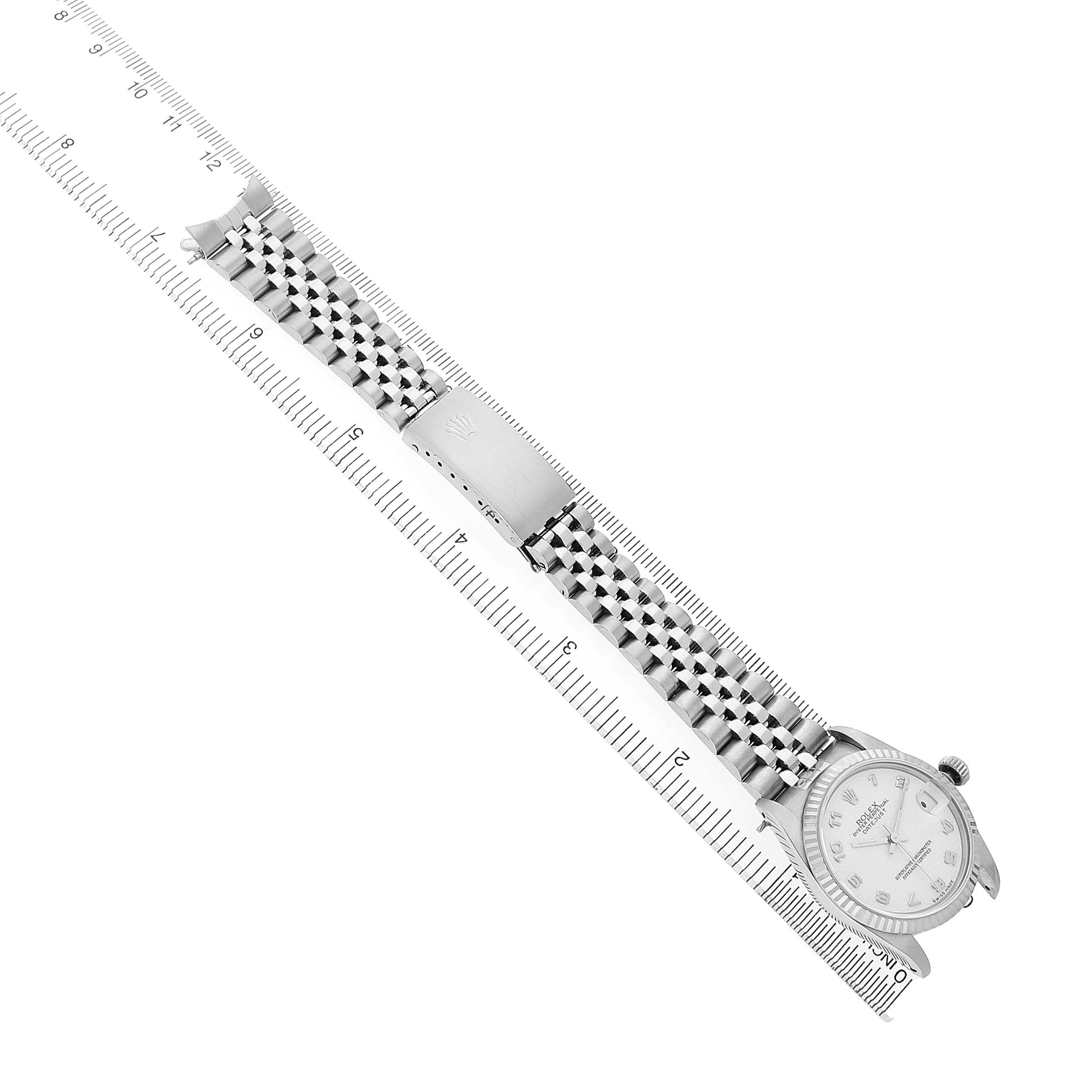 The Rolex Mid-Size 68274 Womens Stainless Steel White Dial watch is shown from a top angle, displaying the case, dial, and bracelet along a ruler.