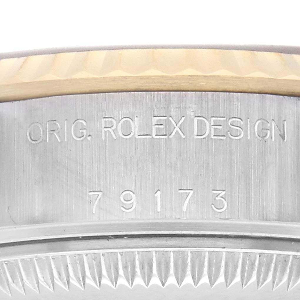 The image shows a close-up of the side of a Rolex Datejust 79173 Women
s Steel and Gold (two tone) Champagne Dial 79173 Women
s Steel and Gold (two tone) Champagne Dial watch case, featuring engraved text and the edge of the bezel.