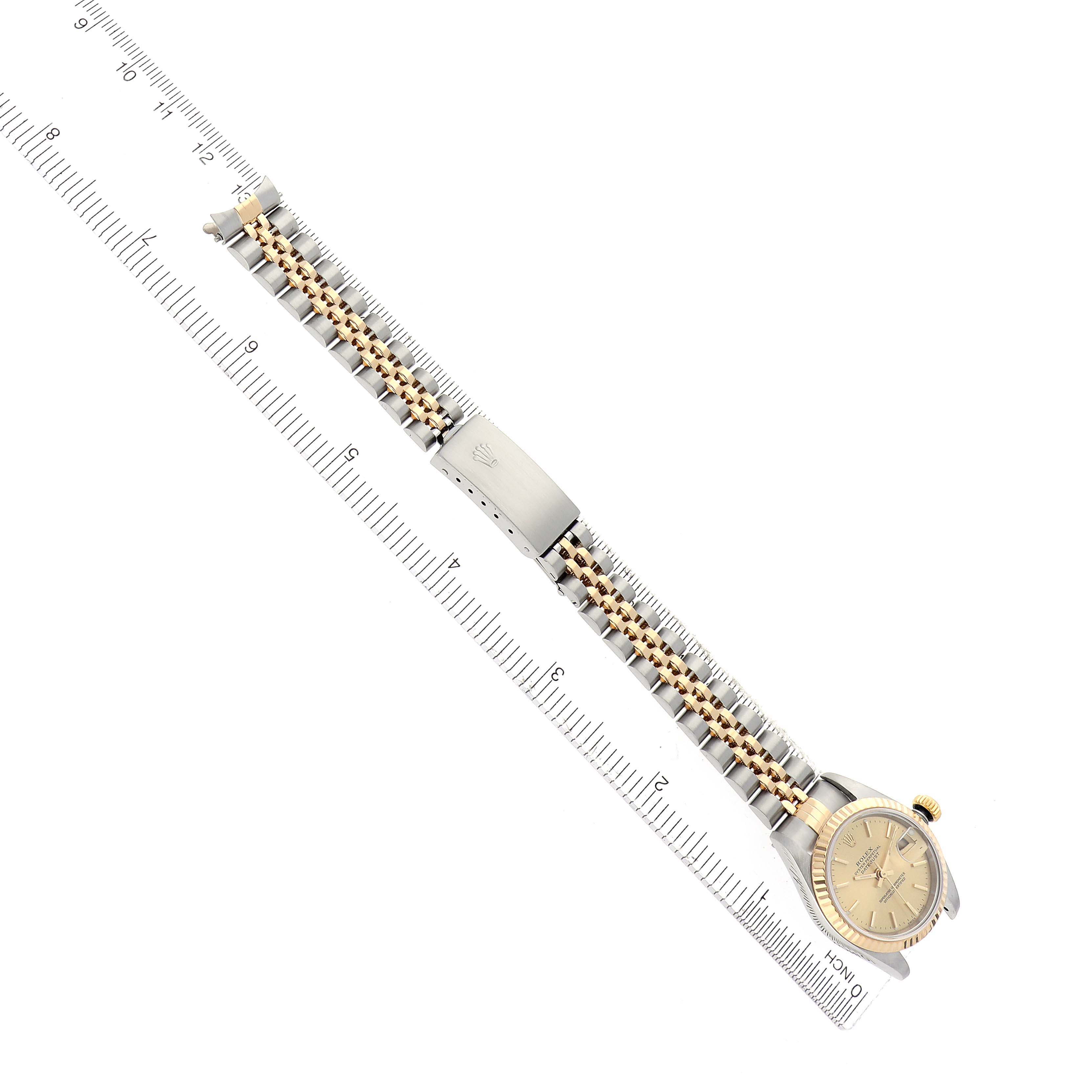 The Rolex Datejust 79173 Women
s Steel and Gold (two tone) Champagne Dial 79173 Women
s Steel and Gold (two tone) Champagne Dial watch is shown from an overhead angle, displaying the dial, bracelet, and clasp next to a ruler.