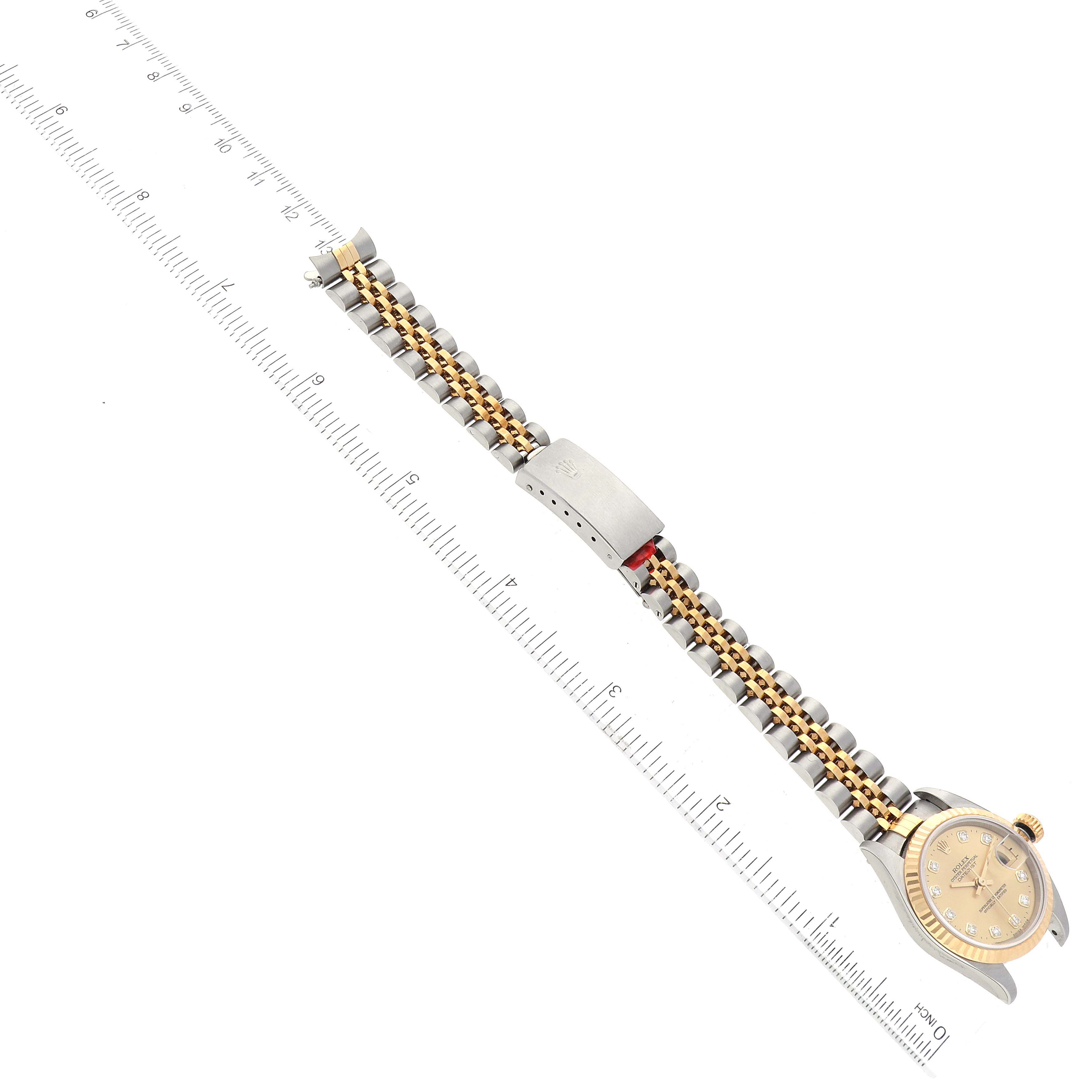 The image shows a top-down view of the Rolex Datejust 79173G Women's Steel and Gold (two tone) Champagne Dial 79173G Women's Steel and Gold (two tone) Champagne Dial watch, including the watch face, two-tone bracelet, and clasp, with a ruler for scale.