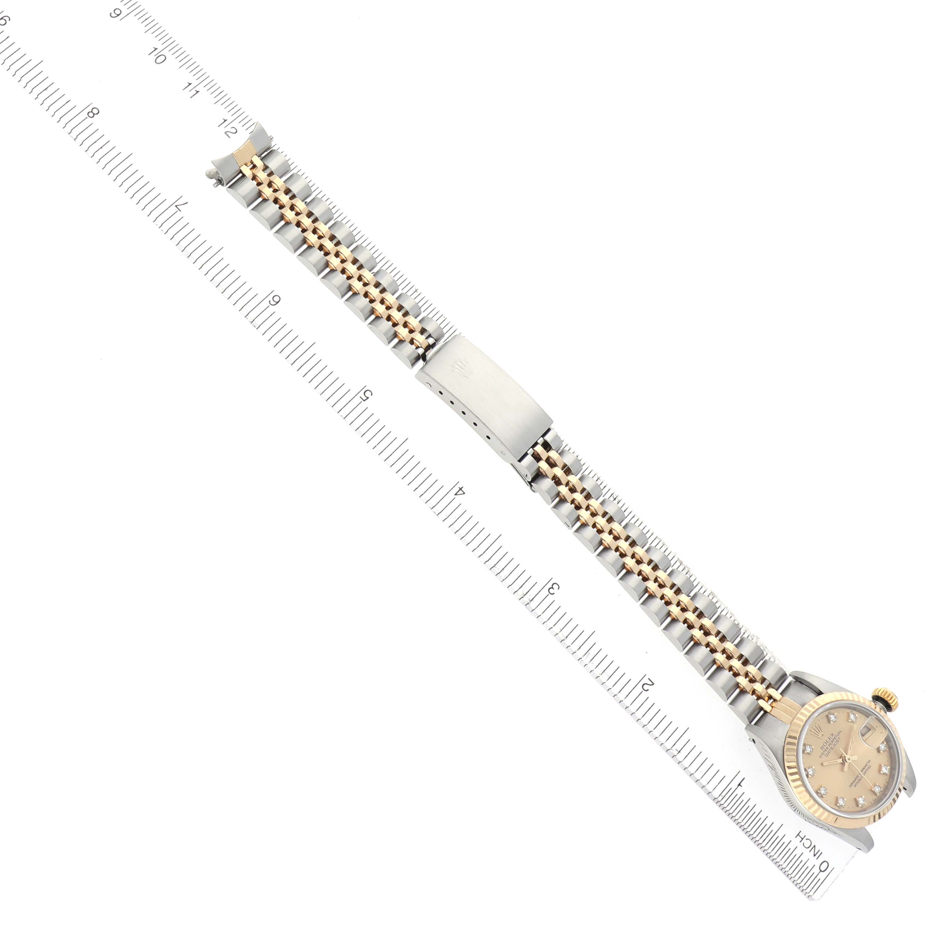 The Rolex Datejust 69173 Women
s Steel and Gold (two tone) Champagne Dial 69173 Women
s Steel and Gold (two tone) Champagne Dial watch is shown from a top-down angle, highlighting the full bracelet, clasp, and dial with a ruler for scale.
