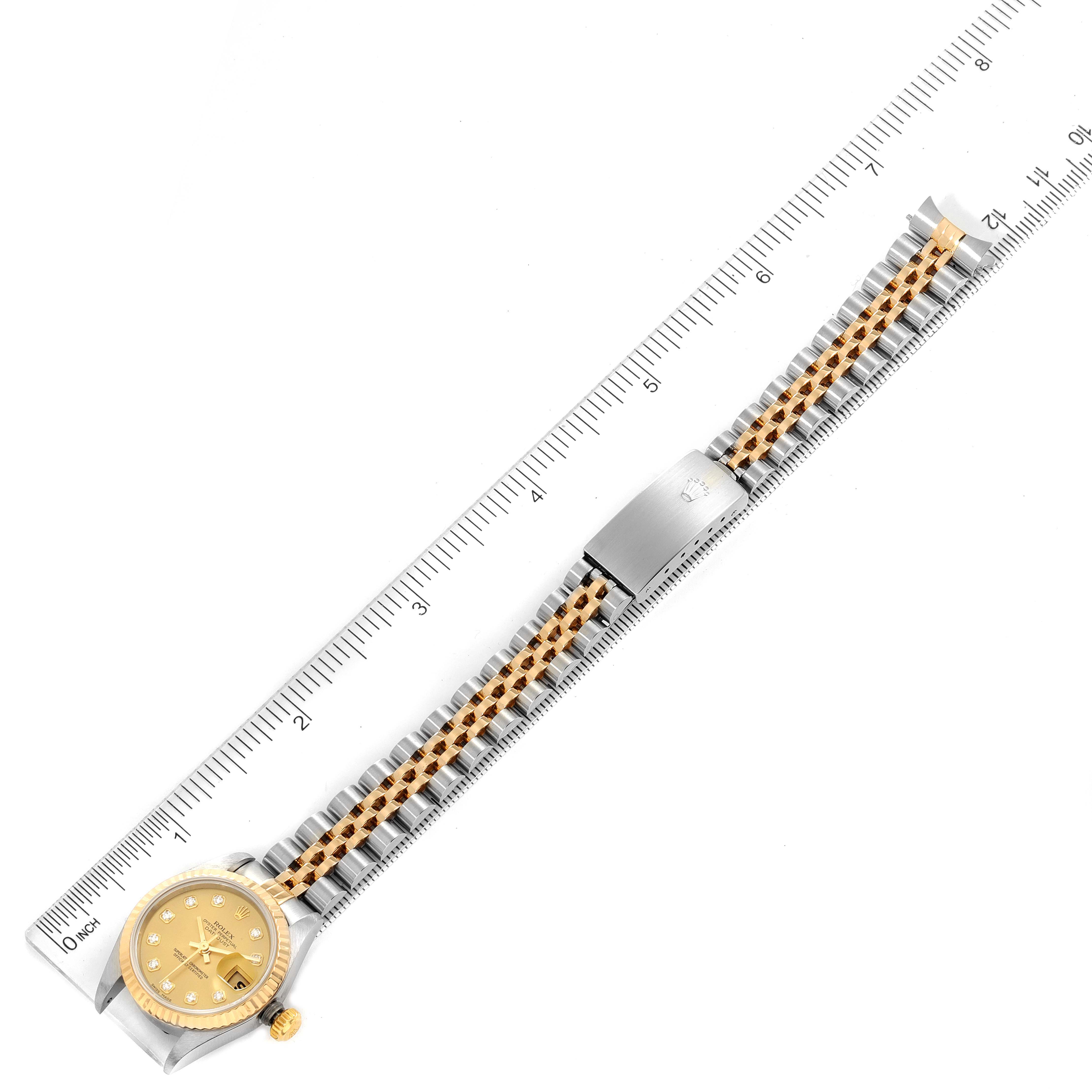 This image shows the entire Rolex Datejust 79173 Women
s Steel and Gold (two tone) Champagne Dial 79173 Women
s Steel and Gold (two tone) Champagne Dial model watch laid flat beside a ruler for scale.