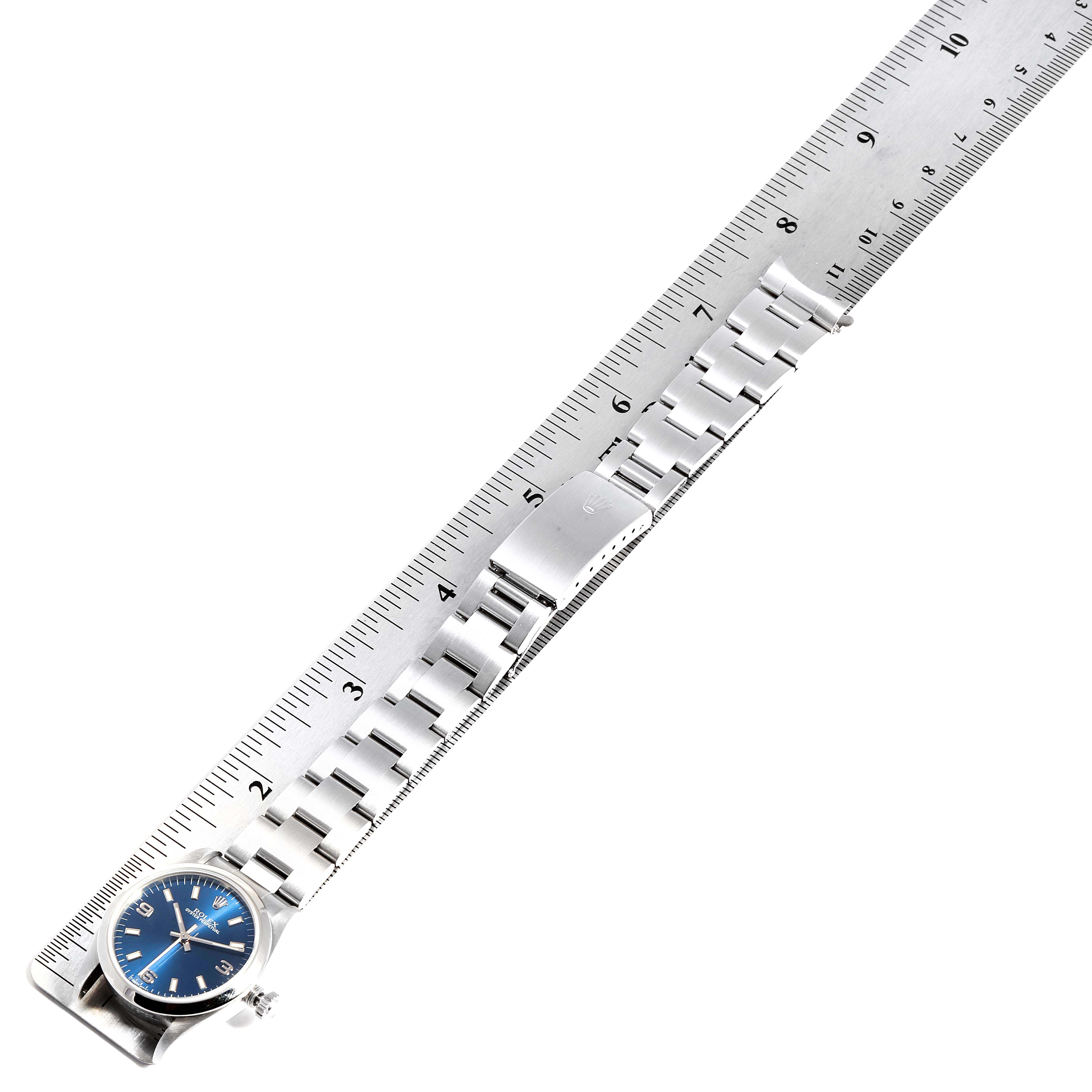 The image shows a Rolex Mid-Size 67480 Women
s Stainless Steel Blue Dial 67480 Women
s Stainless Steel Blue Dial model watch laid flat alongside a ruler, highlighting the bracelet and clasp.