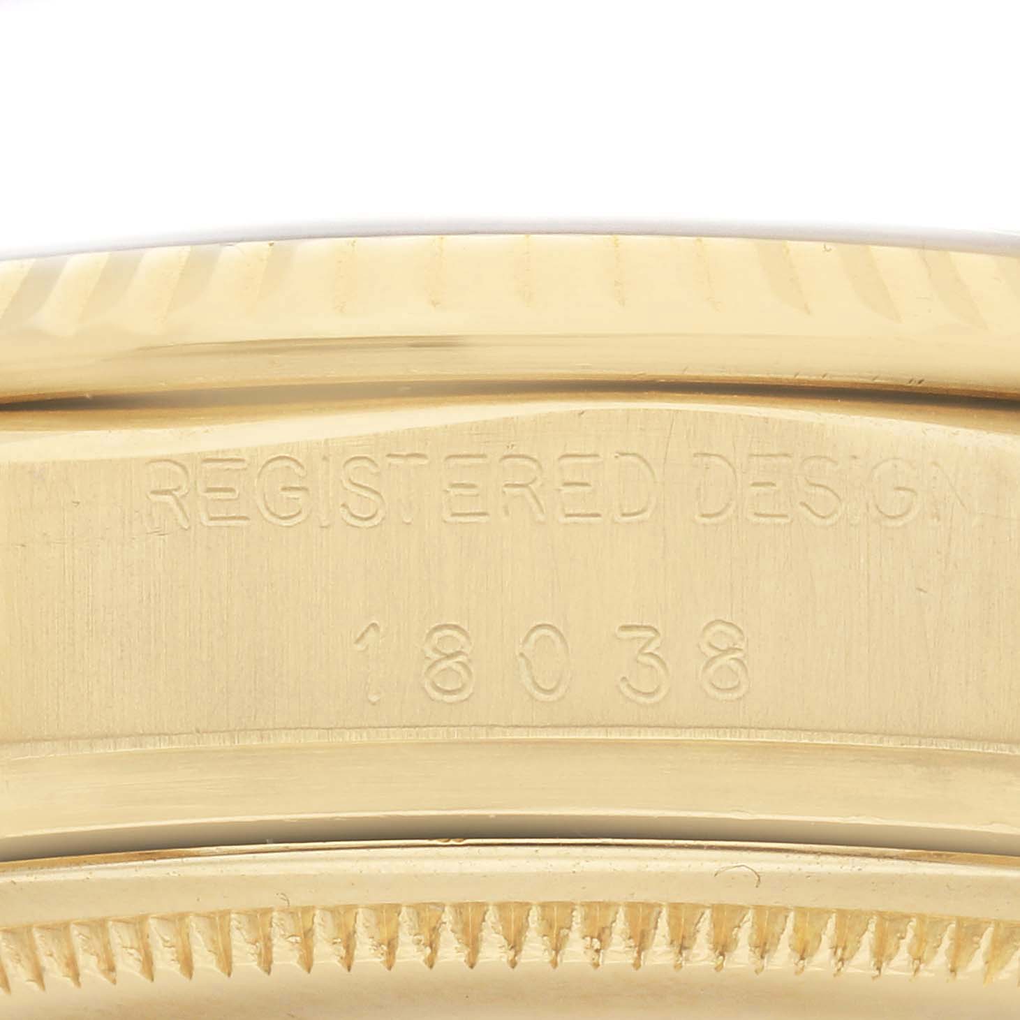 The image shows a close-up of the case side and part of the bezel of a Rolex President 18038 Men
s Yellow Gold Champagne Dial 18038 Men
s Yellow Gold Champagne Dial model, featuring the engraving "REGISTERED DESIGN 18038".